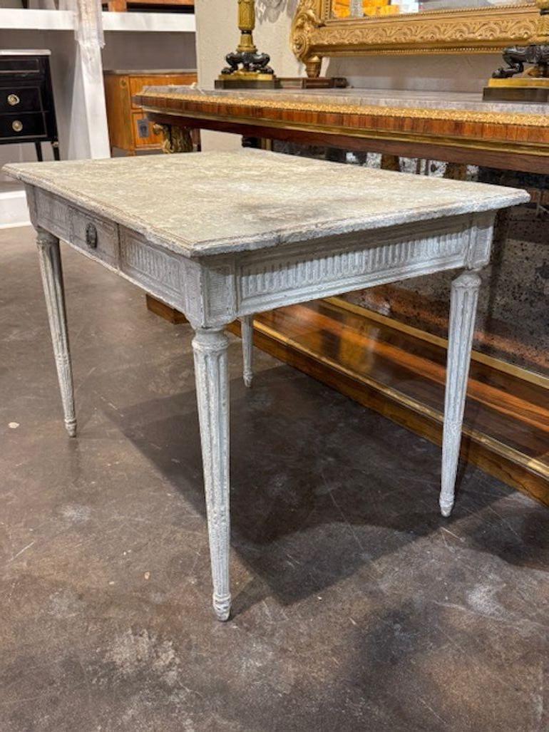 La table à écrire Louis XVI sculptée et peinte du 19e siècle est un beau meuble ancien qui met en valeur le style de l'époque.  et l'élégance du style Louis XVI. Ce bureau présente de magnifiques sculptures et une belle patine, ce qui en fait un
