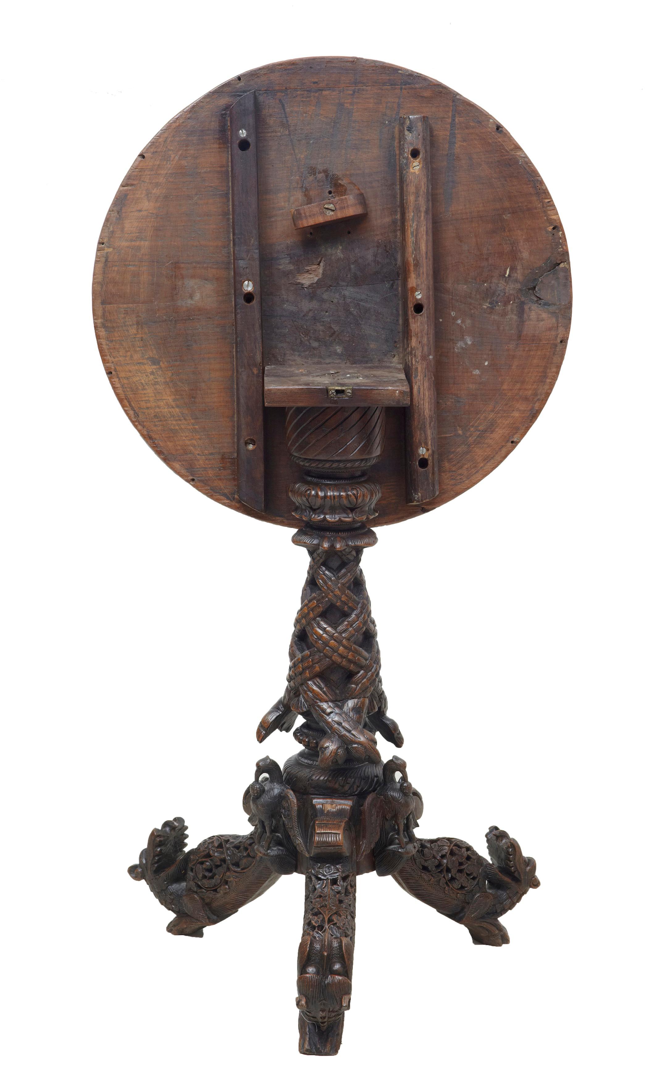 Good quality burmese / Anglo-Indian tilt-top table circa 1880.

Circular top with a carved border of birds, foliage and architecture. Tilting top, which leads down to the carved tripod base. Carved birds and dogs adorn the feet. Age splits to top