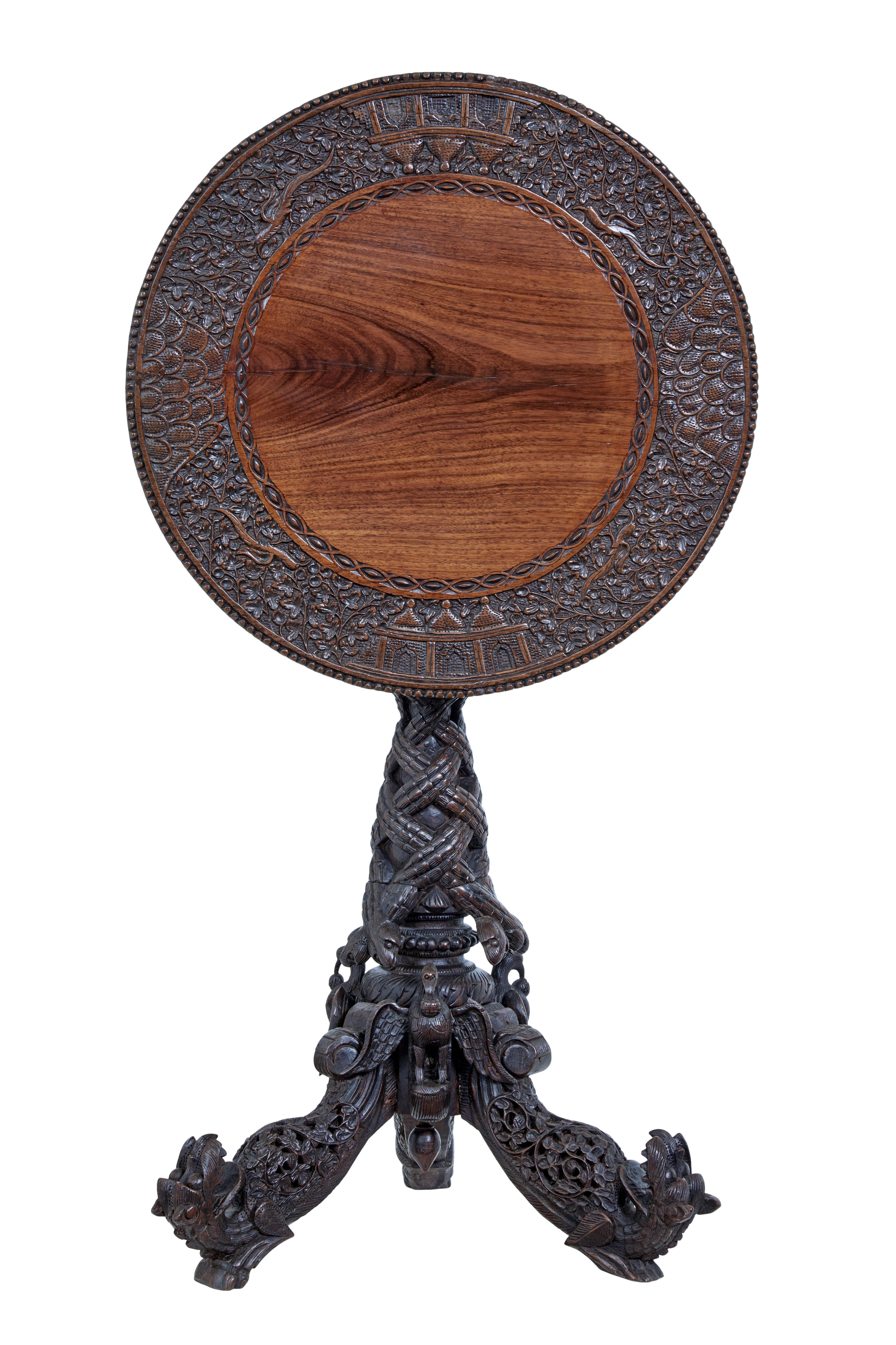 Good quality Burmese / anglo indian tilt top table circa 1880.

Circular top with a carved border of birds, foliage and architecture. Tilting top, which leads down to the carved tripod base. Carved birds and dogs adorn the feet. Age splits to top
