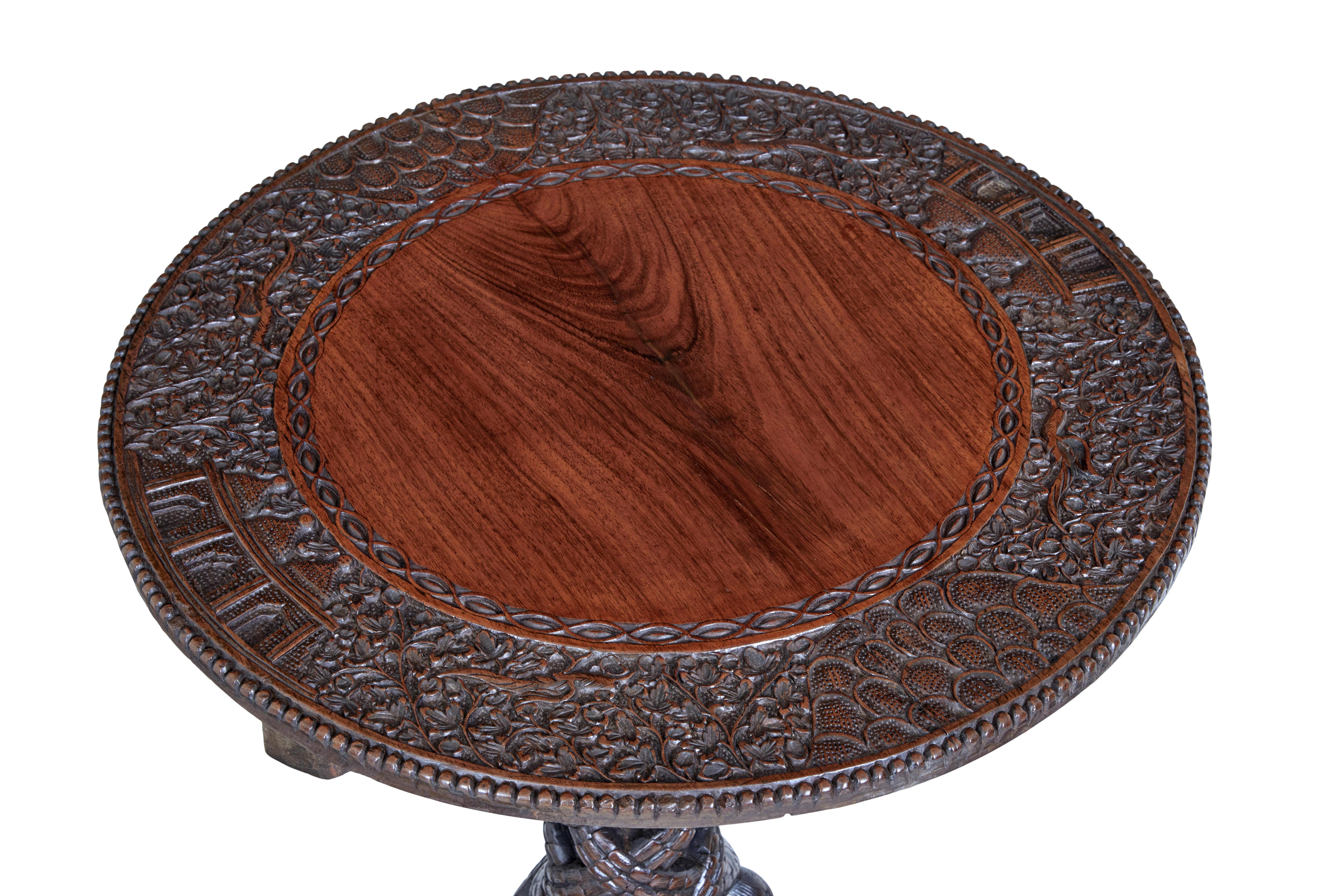 Good quality Burmese / Anglo Indian tilt top table, circa 1880.

Circular top with a carved border of birds, foliage and architecture. Tilting top, which leads down to the carved tripod base. Carved birds and dogs adorn the feet. Age splits to top