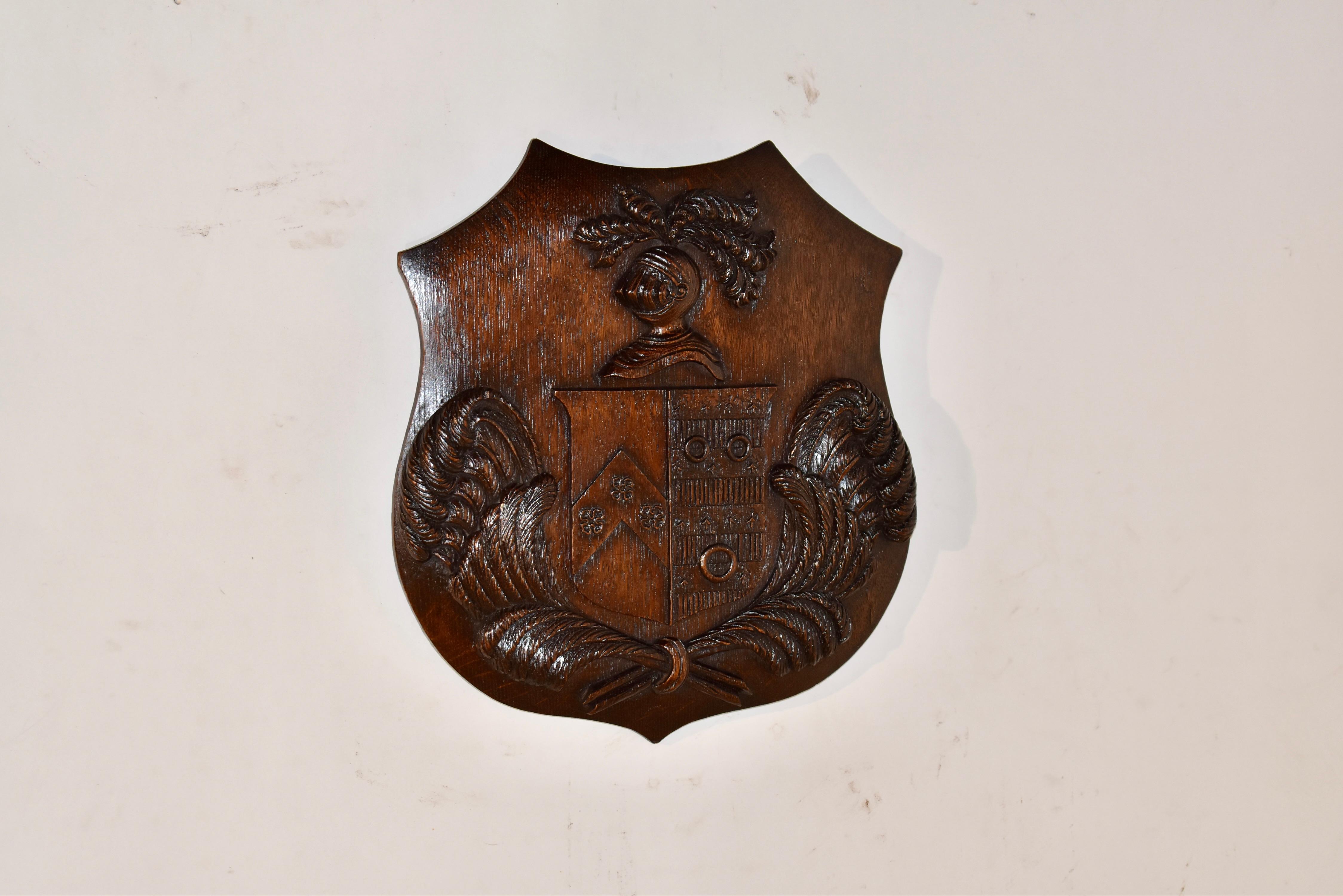 Handgeschnitztes Wappen aus dem 19. Jahrhundert.  Die Plakette hat die Form eines Schildes, auf dem ein Ritterkopf mit Federbüscheln in seiner Rüstung über einem geschnitzten Schild abgebildet ist.  Das Schild befindet sich über wunderschön