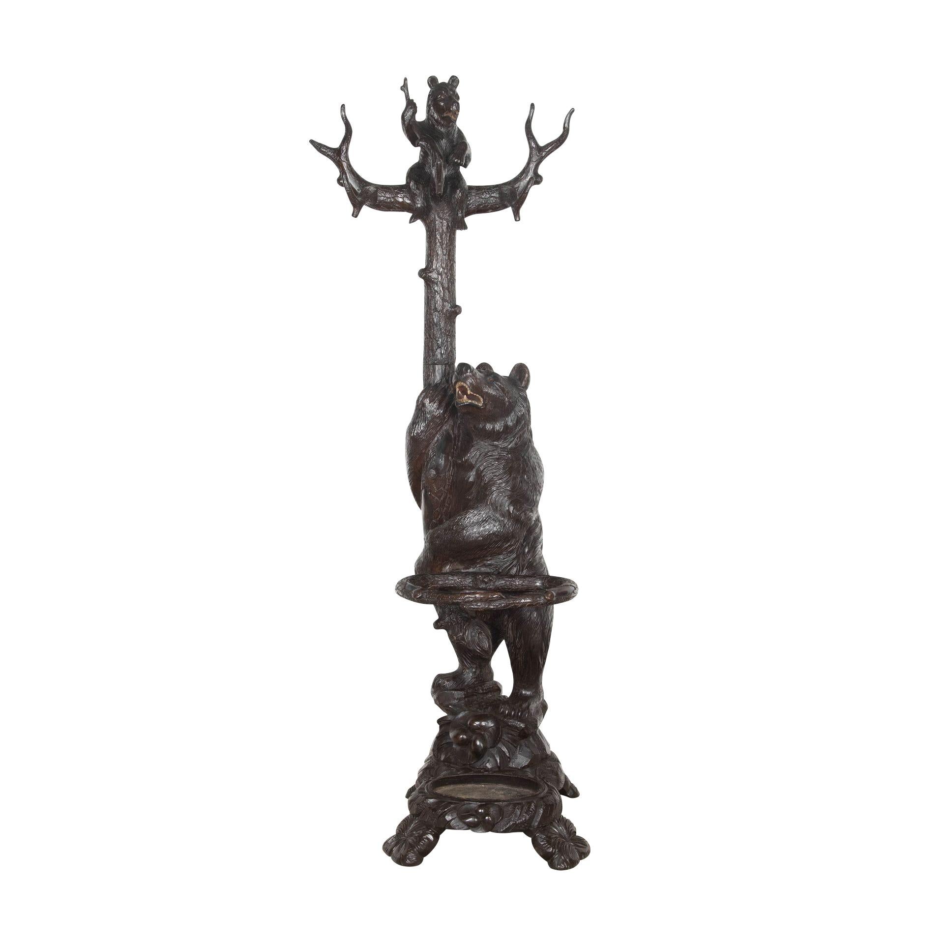 An impressive late 19 century Black Forest carved bear hall stand, of a bear looking up while holding a tree with three branches forming coat/hat hooks, with an inquisitive bear cub centralised. The mother also holding abode branch to create a