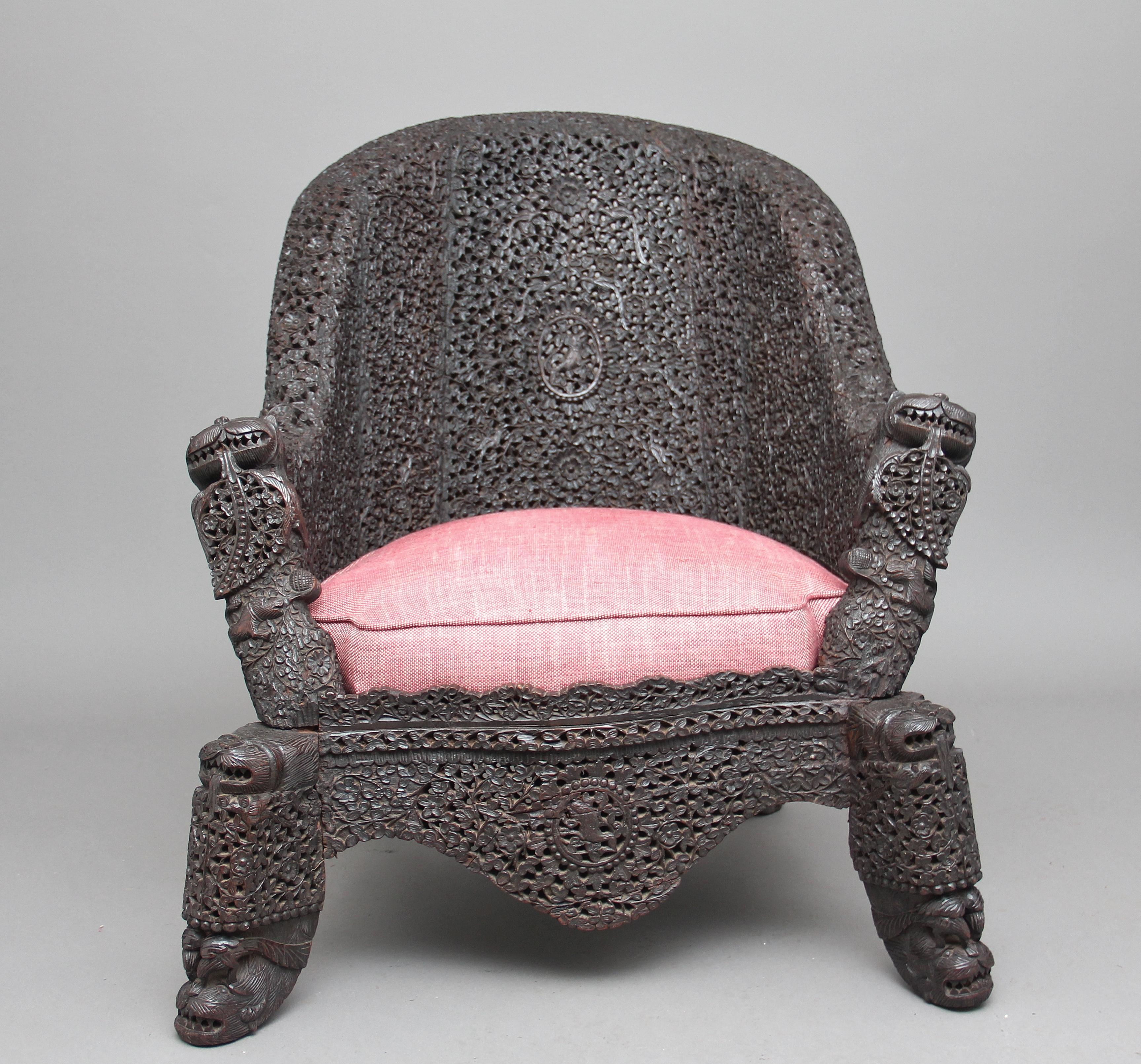 19th century carved hardwood Burmese chair, profusely carved all over with carved fret decoration, with a drop in upholstered seat, mythical figure heads on the arms and top of the legs, the bottom section having a nice carved shaped apron along the