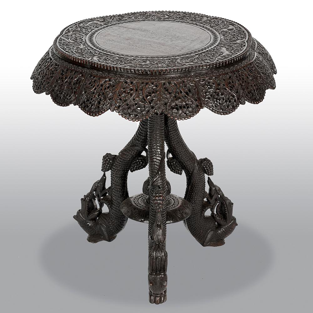 19th century Burmese round walnut end table featuring a carved and filigreed apron as well as a pedestal base ornamented with carved dragon heads on its legs.