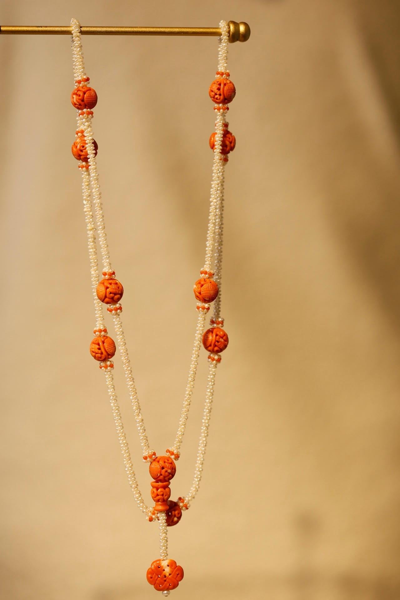 This necklace is made up of ten wonderfully intricate carved coral beads connected by seed pearls in a twisted rope design. There is a pendant of coral, carved in the shape of a stylized Chinese knot, suspended below one bead.

Carved coral of this