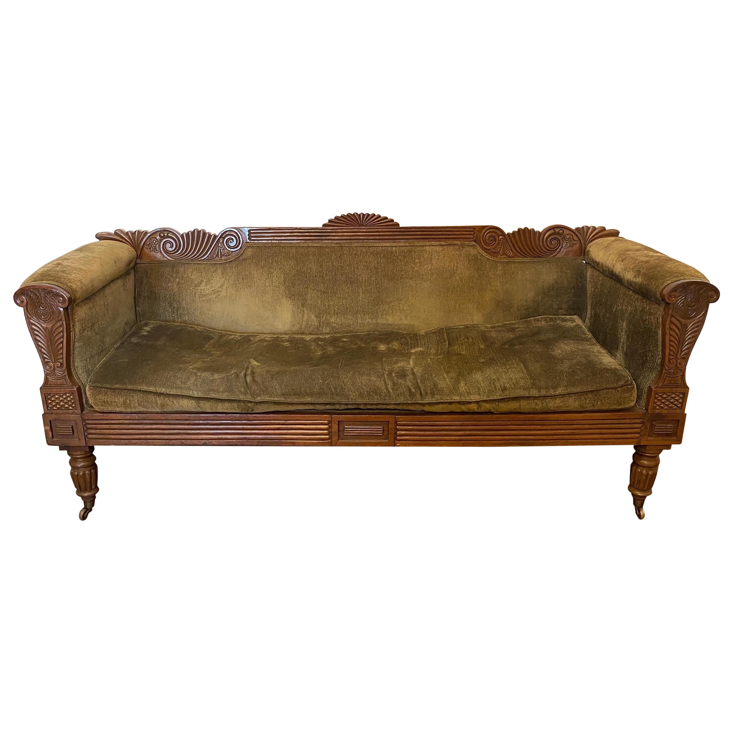 19th century carved English regency sofa with green velvet upholstery and original castors.