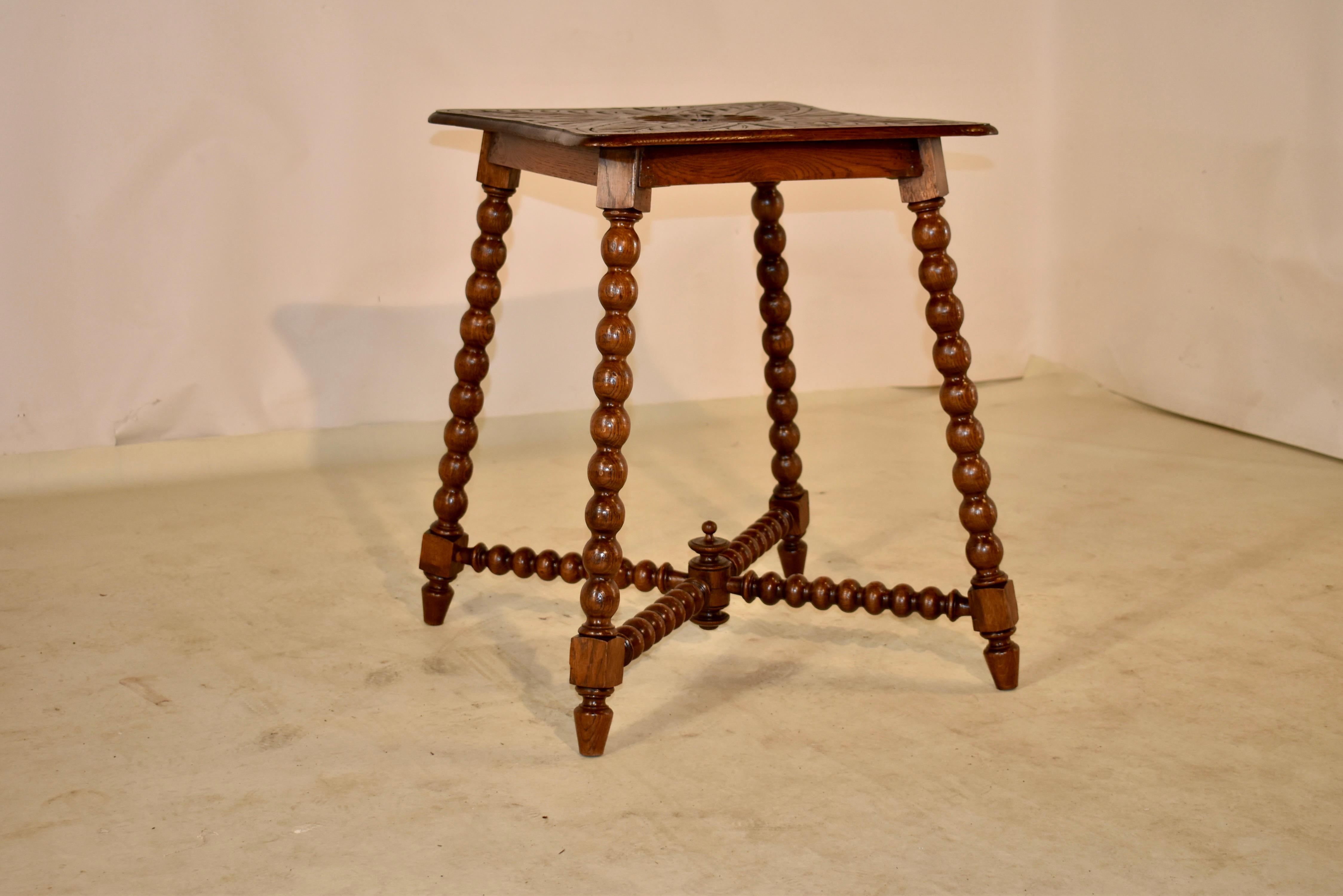 19th Century oak side table from France with a shaped top which has a beveled edge. This follows down to a simple apron and the table is supported on hand turned bobbin style splayed legs. The legs are joined by matching cross stretchers, connected