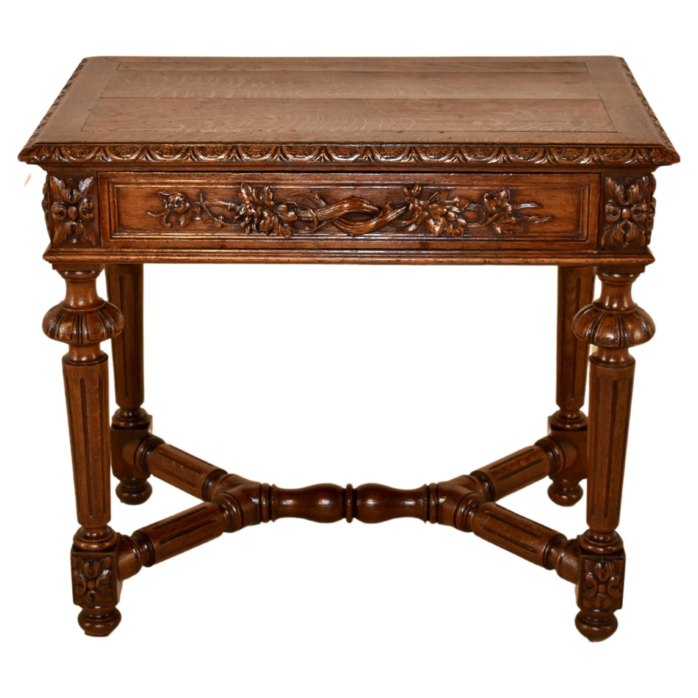 19th century oak side table from France with a banded edge around the top and a beveled edge with hand carved decoration. The top follows down to paneled sides, with three having gorgeous hand carved designs. The back is finished and simple, with no