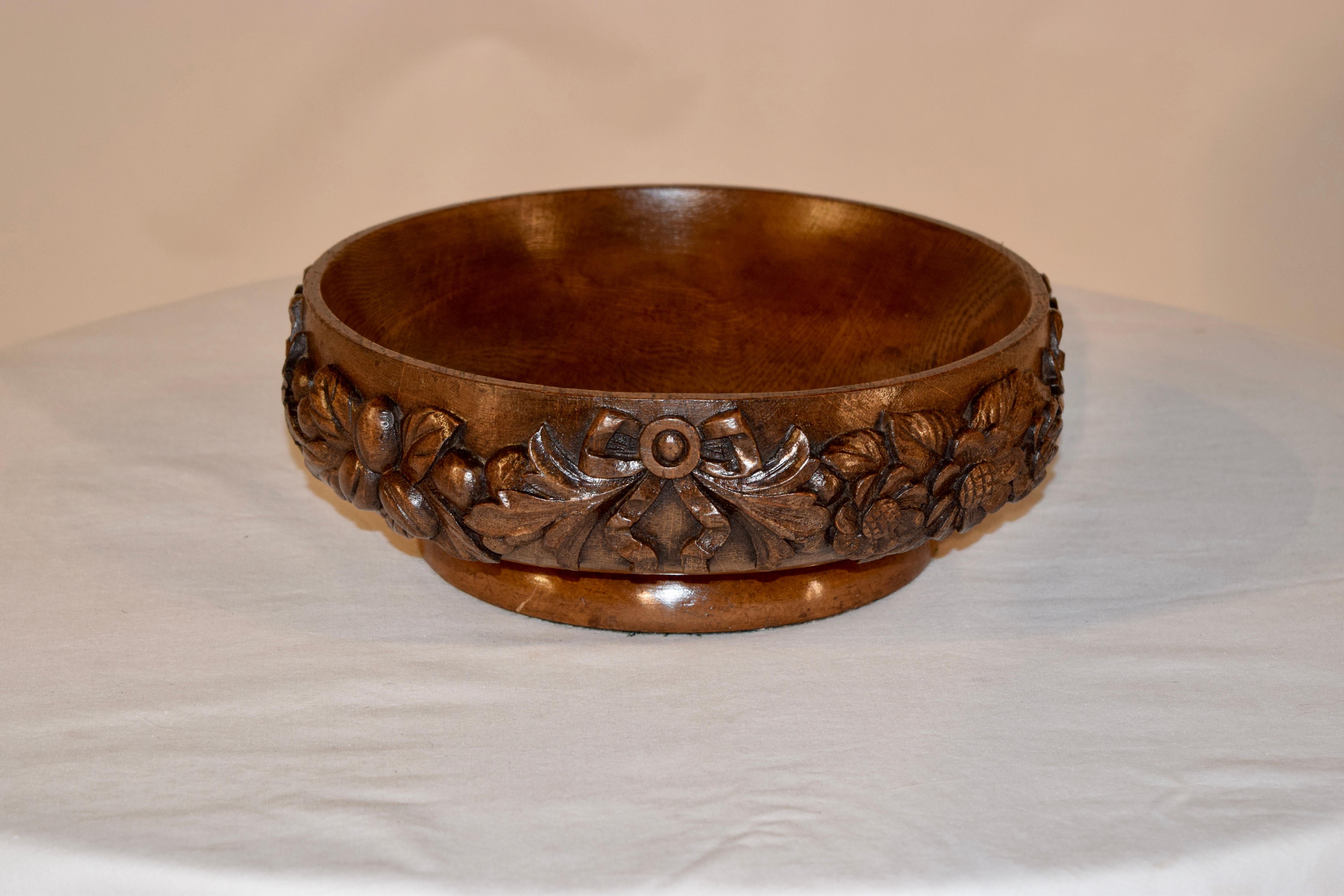 19th century oak fruit bowl from England with lovely hand carved decoration of bows and florals all the way around the outside, supported on a turned base.