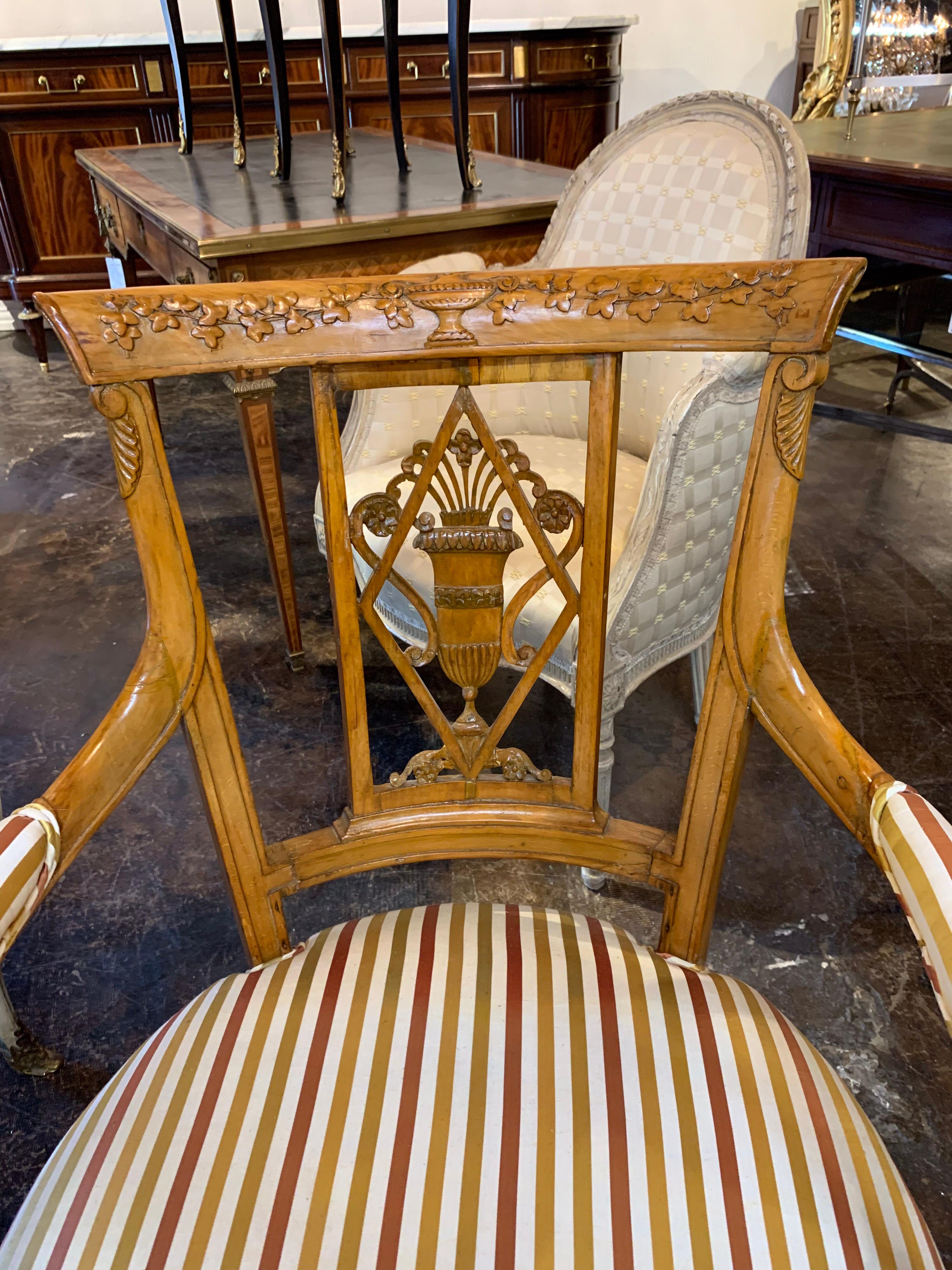 Beautiful pair of carved fruitwood armchairs from England in the neoclassical style. The carvings have an urn with overflowing flowers and vines. The chairs are upholstered in silk with the colors, crème, copper and gold.