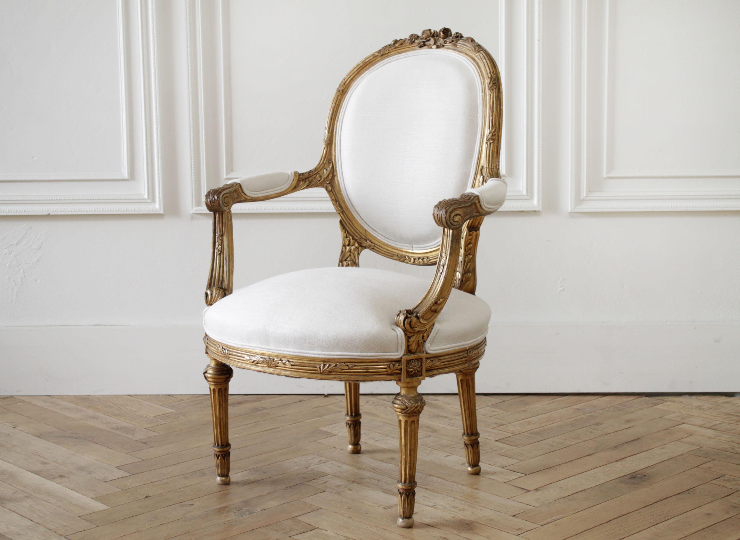 19th century carved giltwood French Louis XVI style open armchairs beautiful original gilt patina with subtle distressed edges. We have reupholstered these in a softened light natural colored linen. Very solid and sturdy, ready for everyday
