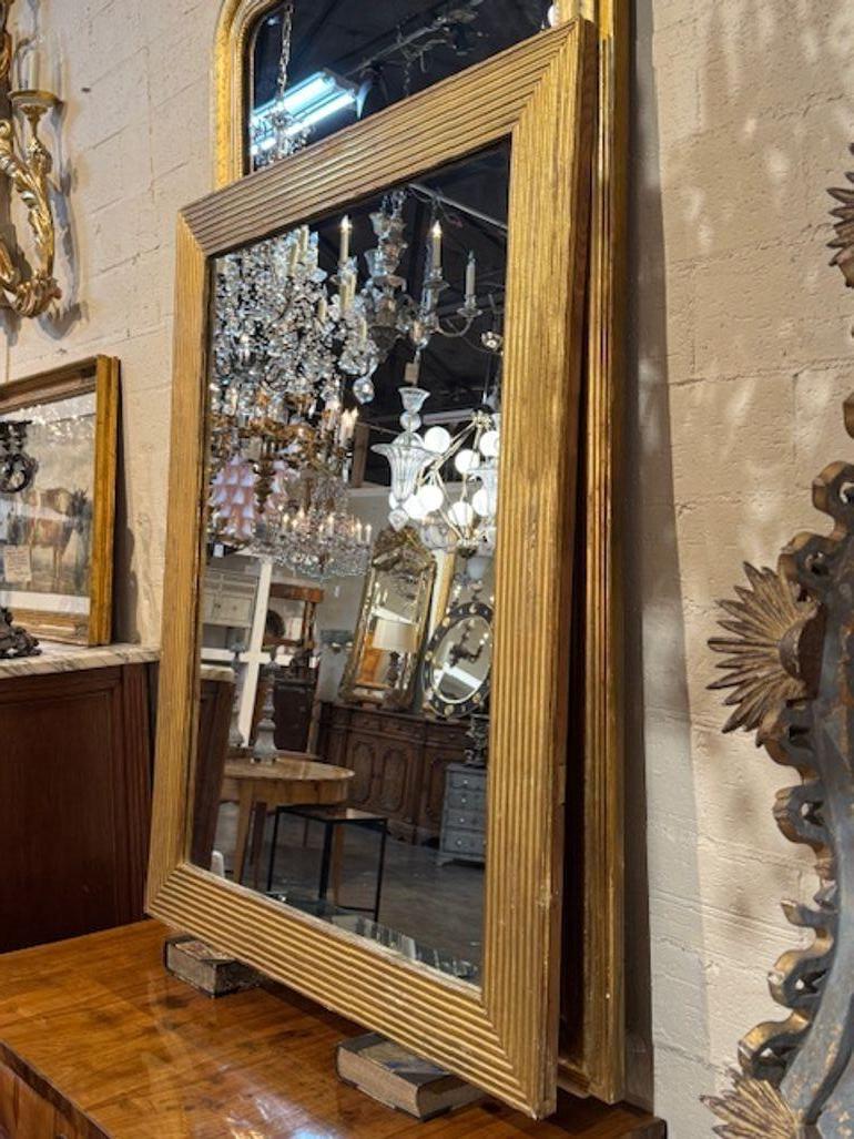 This 19th Century French Giltwood Transitional Mirror adds a touch of elegance and sophistication to any room. The intricate design and craftsmanship of this antique piece make it a unique and timeless addition to furniture arrangements. Perfect for