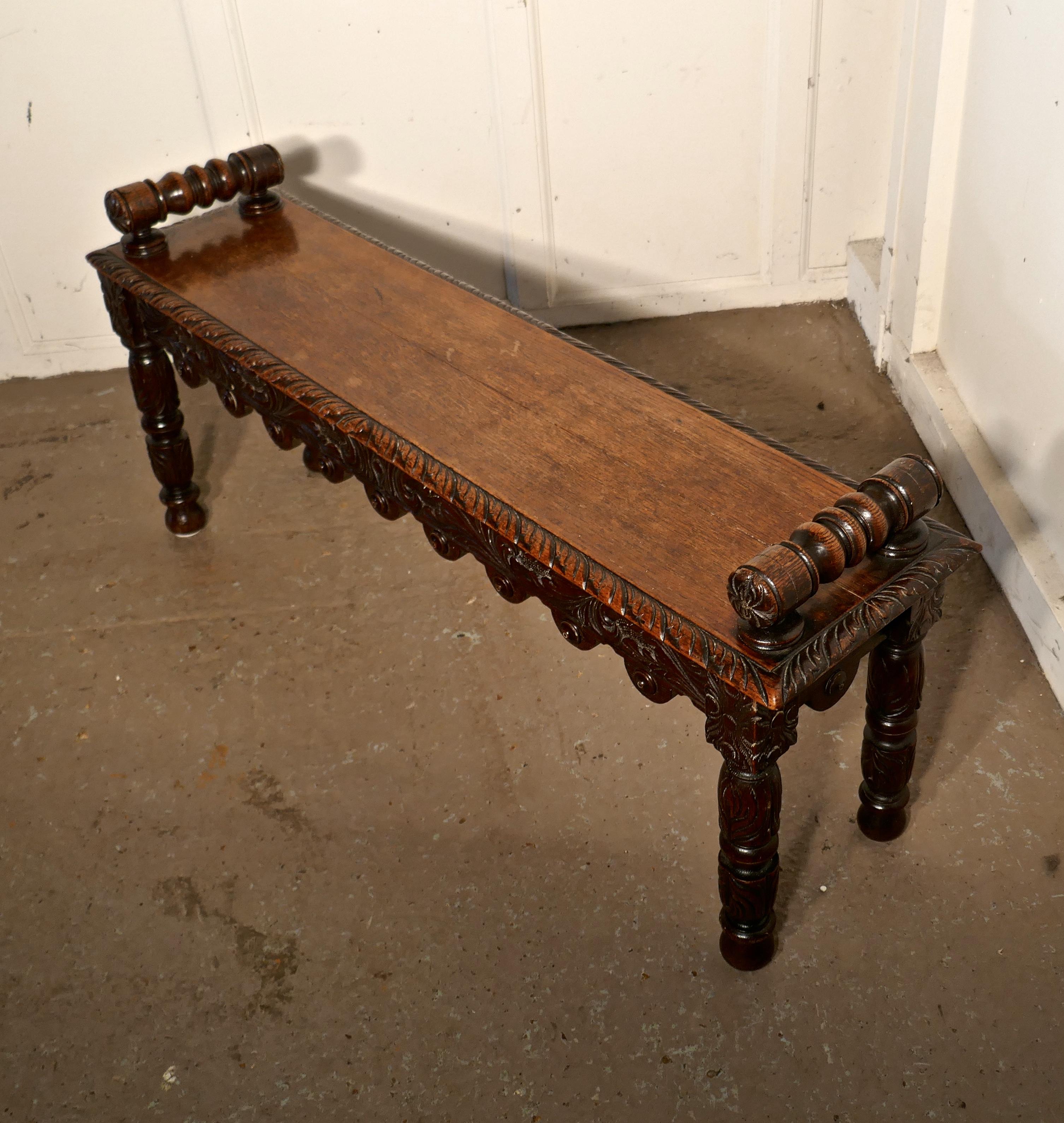 19th century carved Gothic oak window seat or hall bench.

This a lovely piece of carved furniture, it has a solid oak seat with carved front and side edges and a carved scalloped apron beneath, even the legs and arm rests are carved
This is a