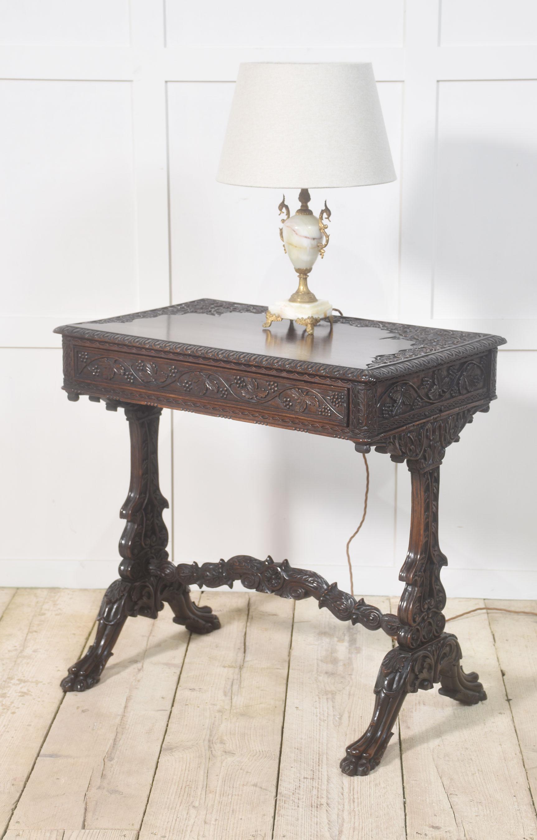Table d'appoint en acajou du XIXe siècle. Le plateau est bien structuré et présente des sculptures détaillées représentant des fruits et des vignes. La frise est équipée d'un long tiroir. Relevée sur des supports d'extrémité très décréptifs réunis