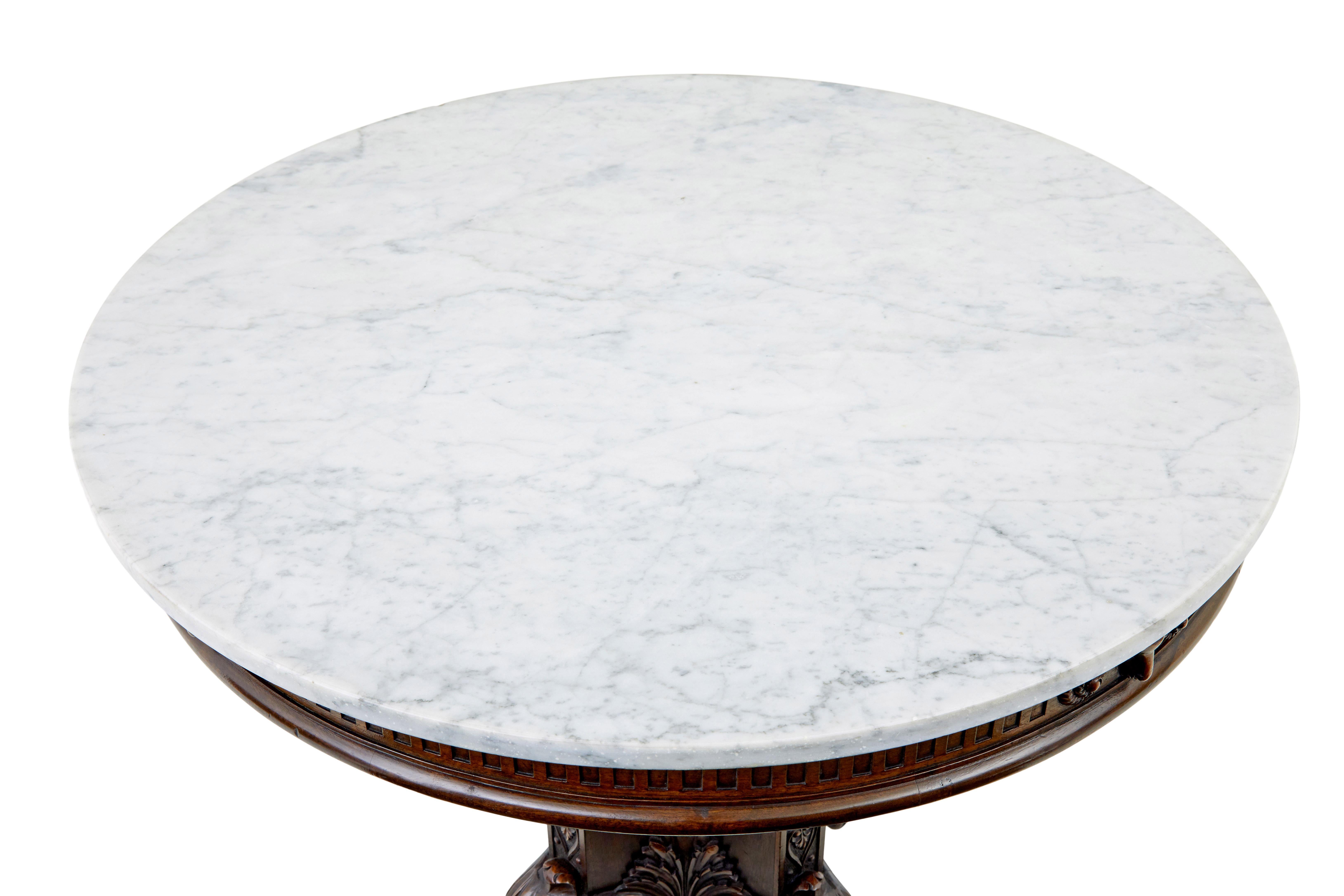 Mesa central de roble tallado y mármol del siglo XIX, hacia 1880.

Mesa de centro circular con tapa de mármol de gran calidad.  Mármol blanco con vetas grises y borde redondeado, asentado sobre un friso de cabezas de carnero talladas, estriado y
