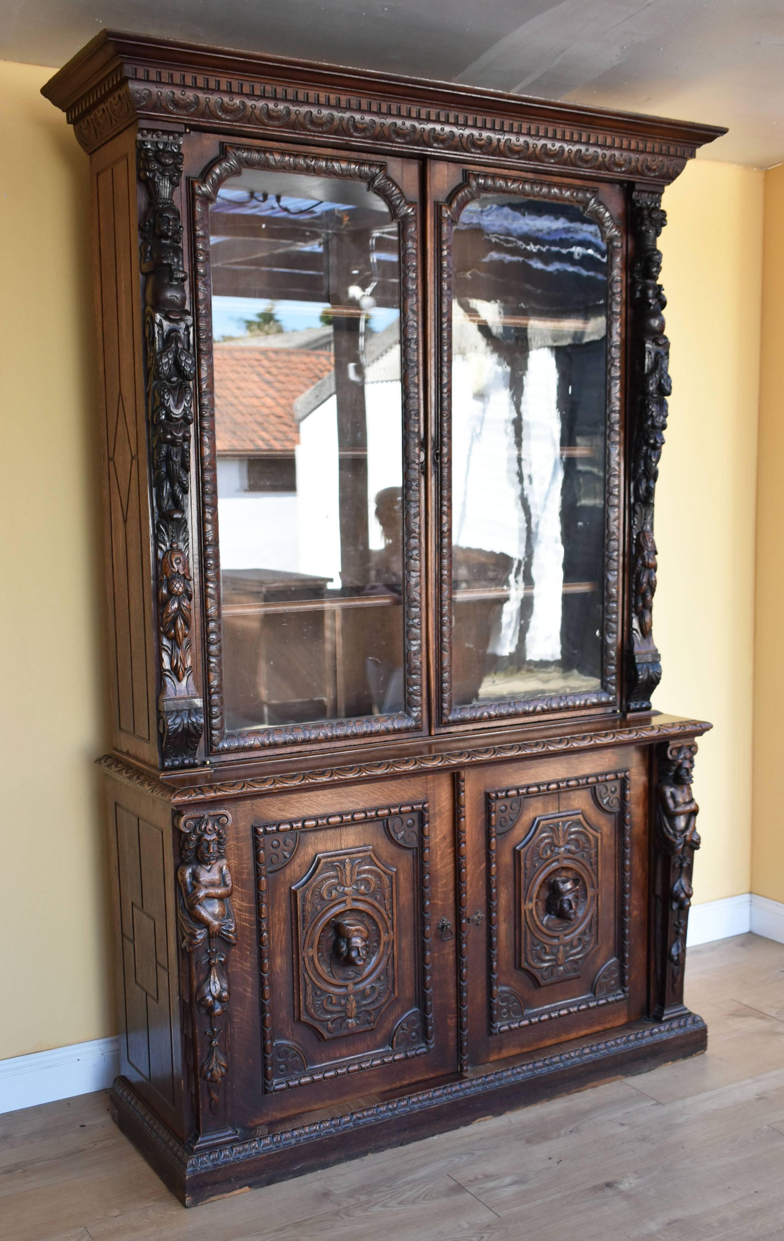 For sale is a good quality Victorian carved oak bookcase. The top having two glazed doors, between foliate carved stiles, the base has a pair of doors, each with a carved mask to the centre, between figural brackets. The piece is in good condition,