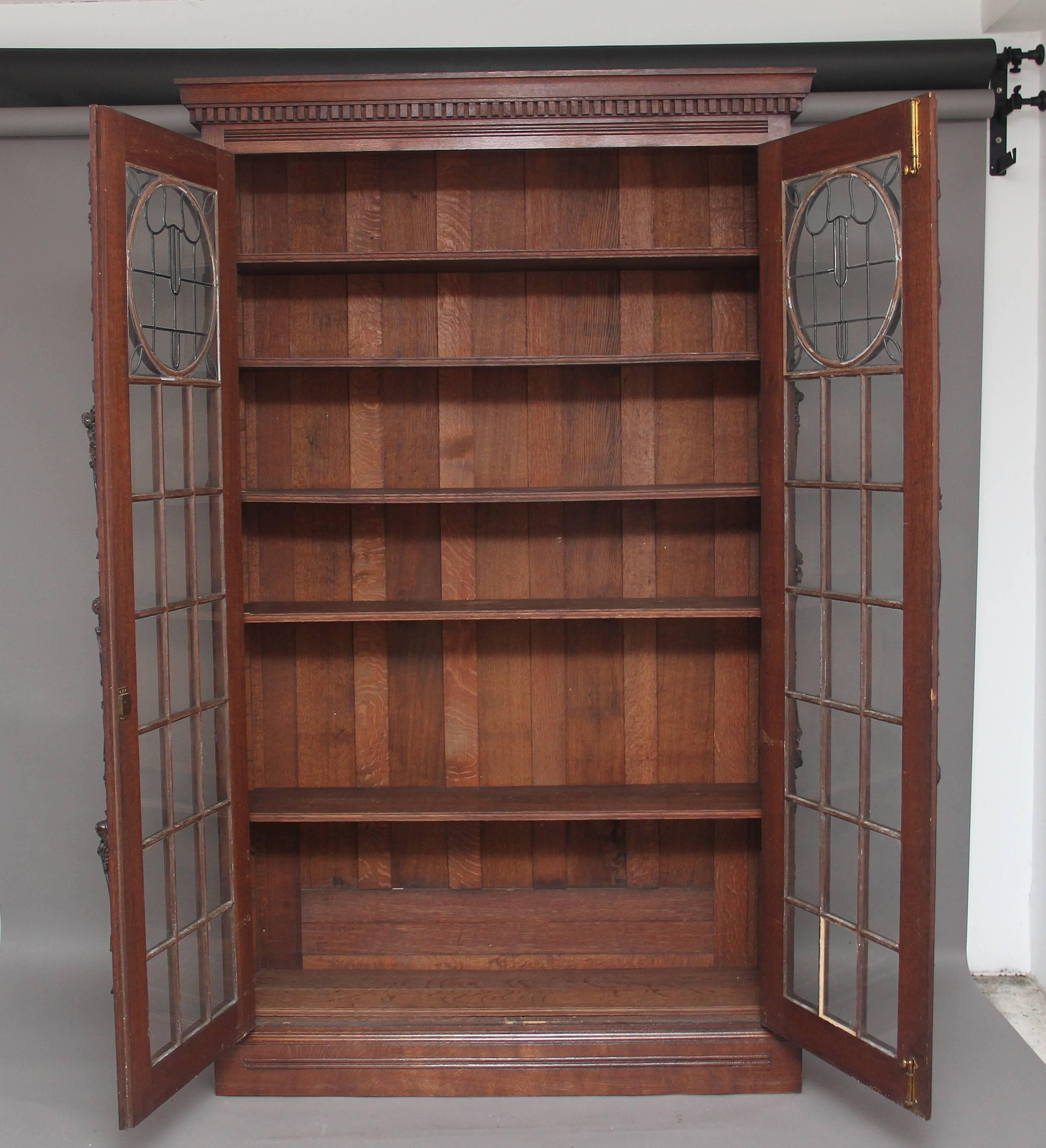 A large 19th century carved oak bookcase in the arts and craft style, having a moulded edge cornice decorated with dentil moulding, the bookcase enclosed with a pair of mackintosh style leaded light astragal glazed doors opening to reveal six