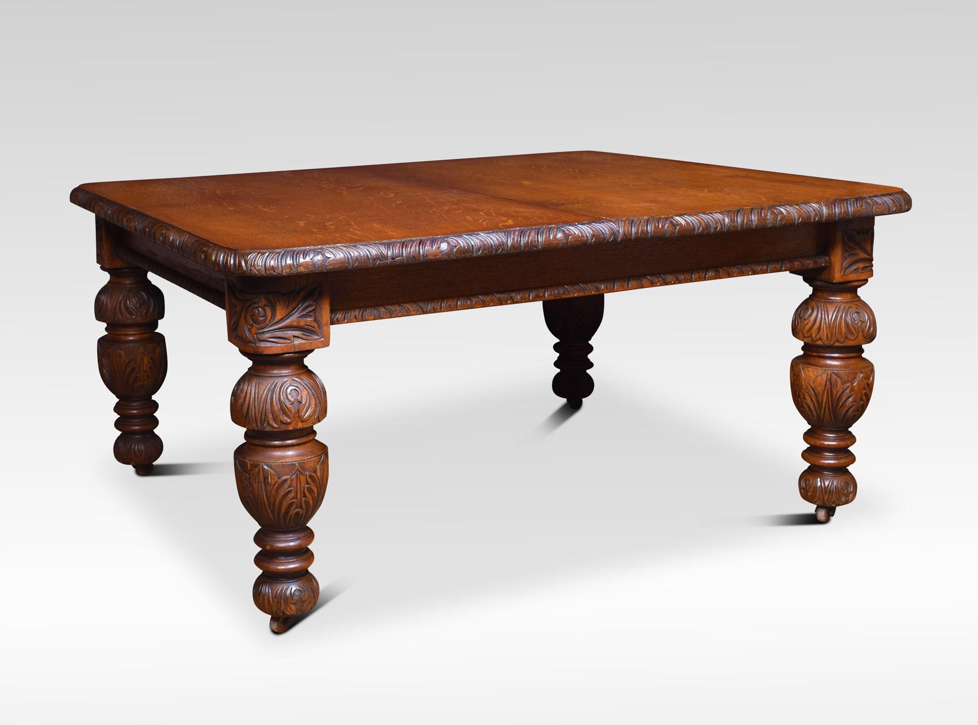 Oak extending dining table, the rectangular top with rounded corners and scrolling carved edge, the telescopic action opening to incorporate three original leaves. All raised up on four foliated carved baluster legs terminating in ceramic