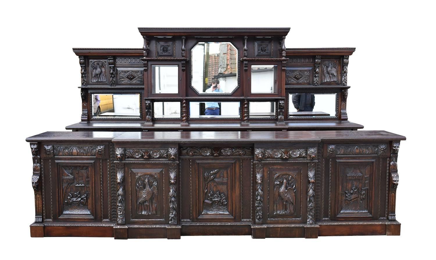 For sale is a 19th century carved oak front and back bar. The centre of the back section has three leaded glass panels to the top, over carved panels and a large bevelled mirror in the centre, flanked by two glass cupboards, each with mirrors in the