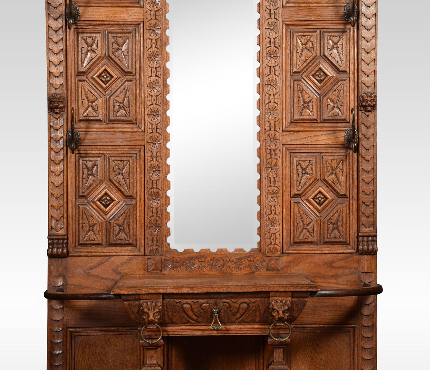 19th century oak hall stand the projecting cornice above original beveled mirror plate. Surrounded by six scrolling hooks. The base section fitted with central draw having umbrella stands to either side with original drip trays. All raised up on bun