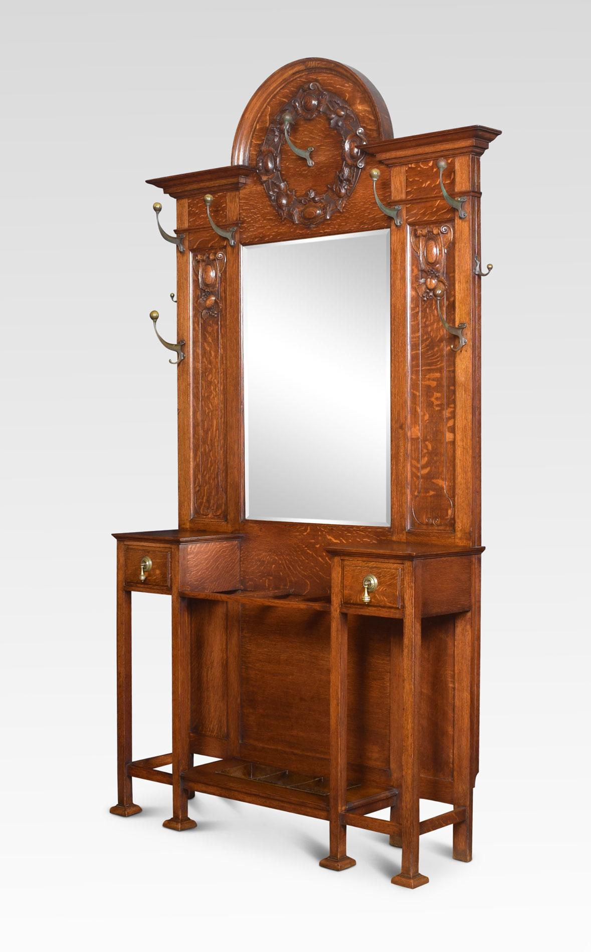 19th century oak hall stand the projecting cornice above the original bevelled mirror plate. Surrounded scrolling hooks. The base section fitted with two short drawers and a central umbrella stand with original drip trays. All raised up on tapering