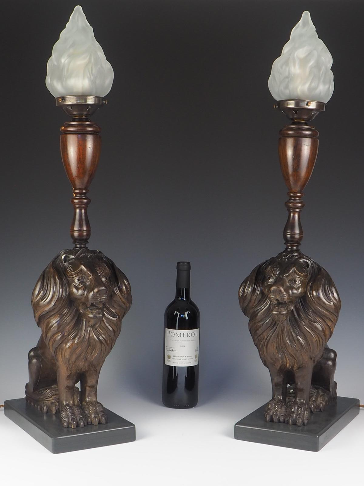 Pair of 19th century carved oak lion lamps

Beautiful pair of carved oak lion lamps with frosted glass flame shade. This 19th century pair of table lamps each features a lion sitting proudly on a grey slate base, propped on its front legs, with