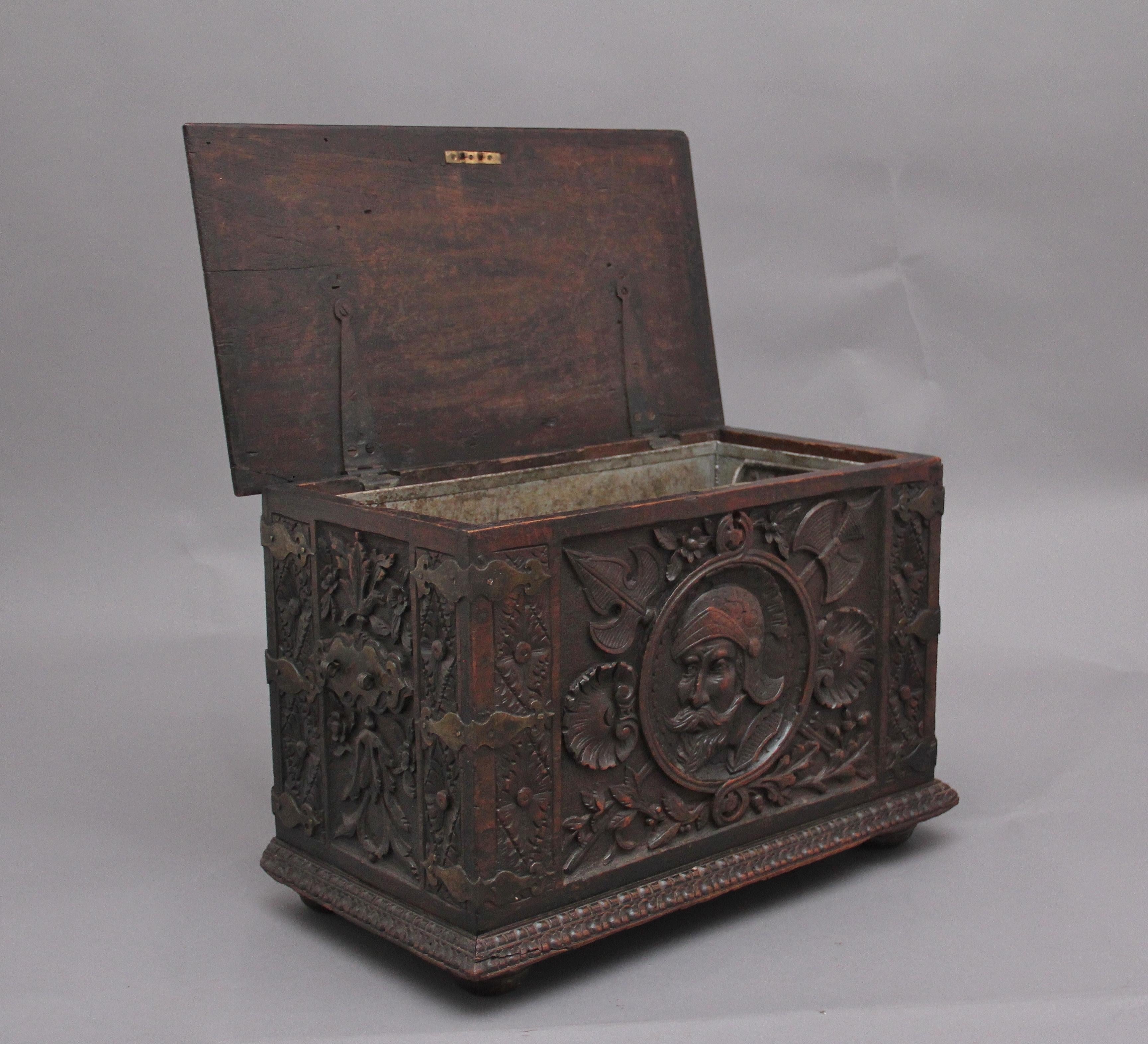 19th century carved oak log box, profusely carved all over, the top having a coat of arms with dragons either side, the hinged top opening to reveal a large storage space for logs, the corners having brass straps, standing on turned bun feet. Lovely
