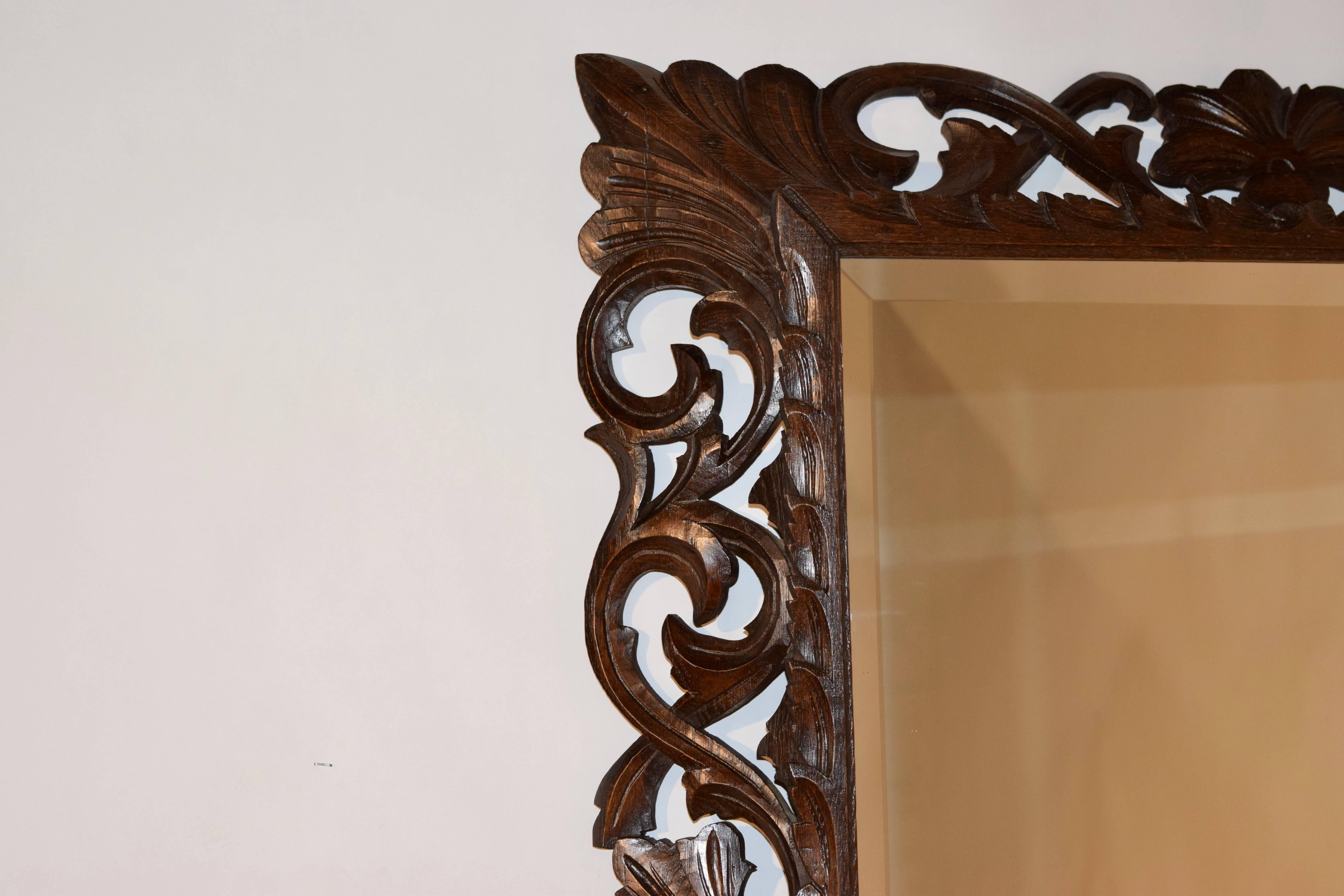 19th Century English oak hand-carved frame with leaves and scrolls surrounding a bevelled mirror.