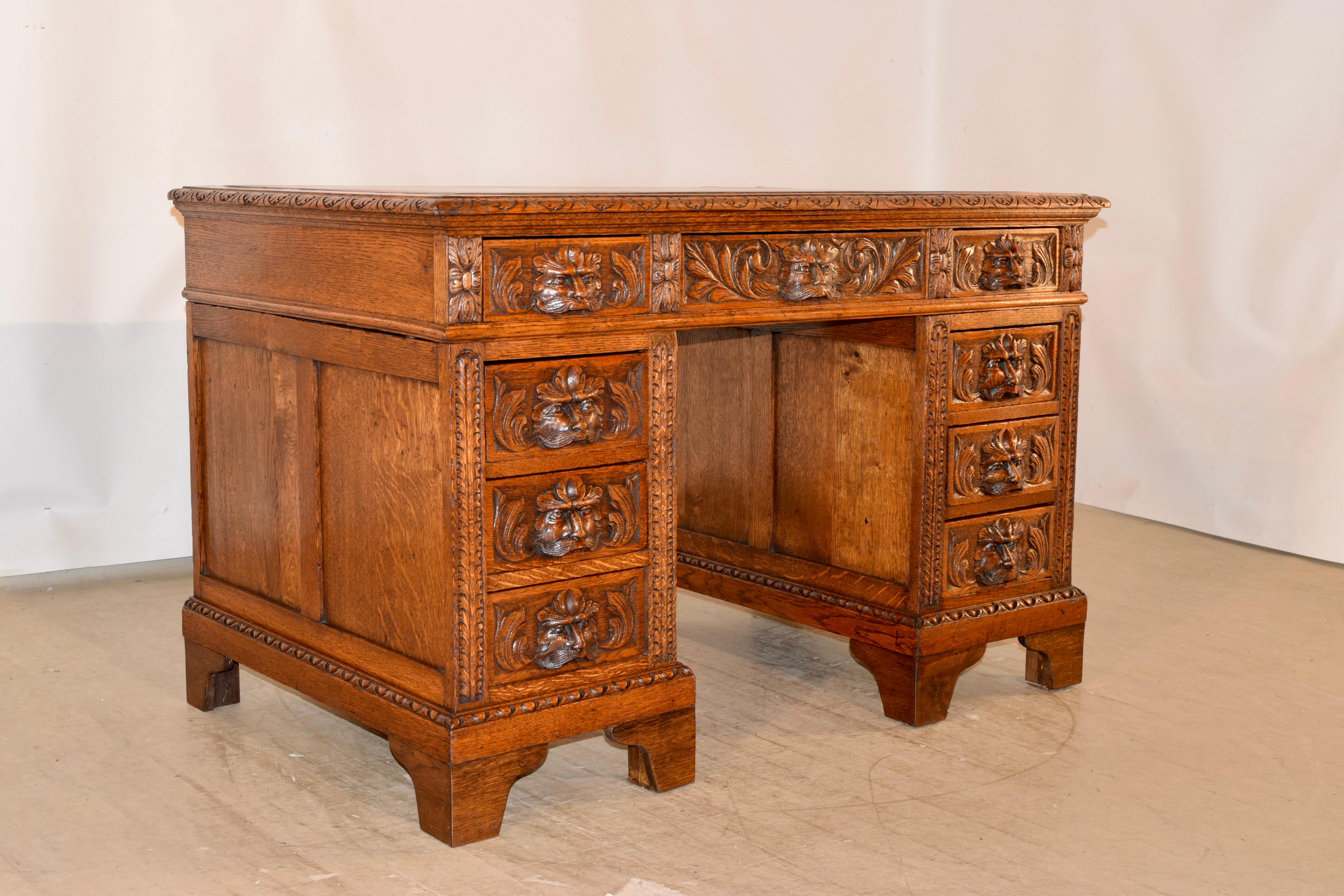 19th century English pedestal desk made from oak. The top is covered in the original brown leather, which has aged beautifully, and is banded by an oak border, which has a gorgeous beveled and carved lunette edge. The desk is in a wonderfully