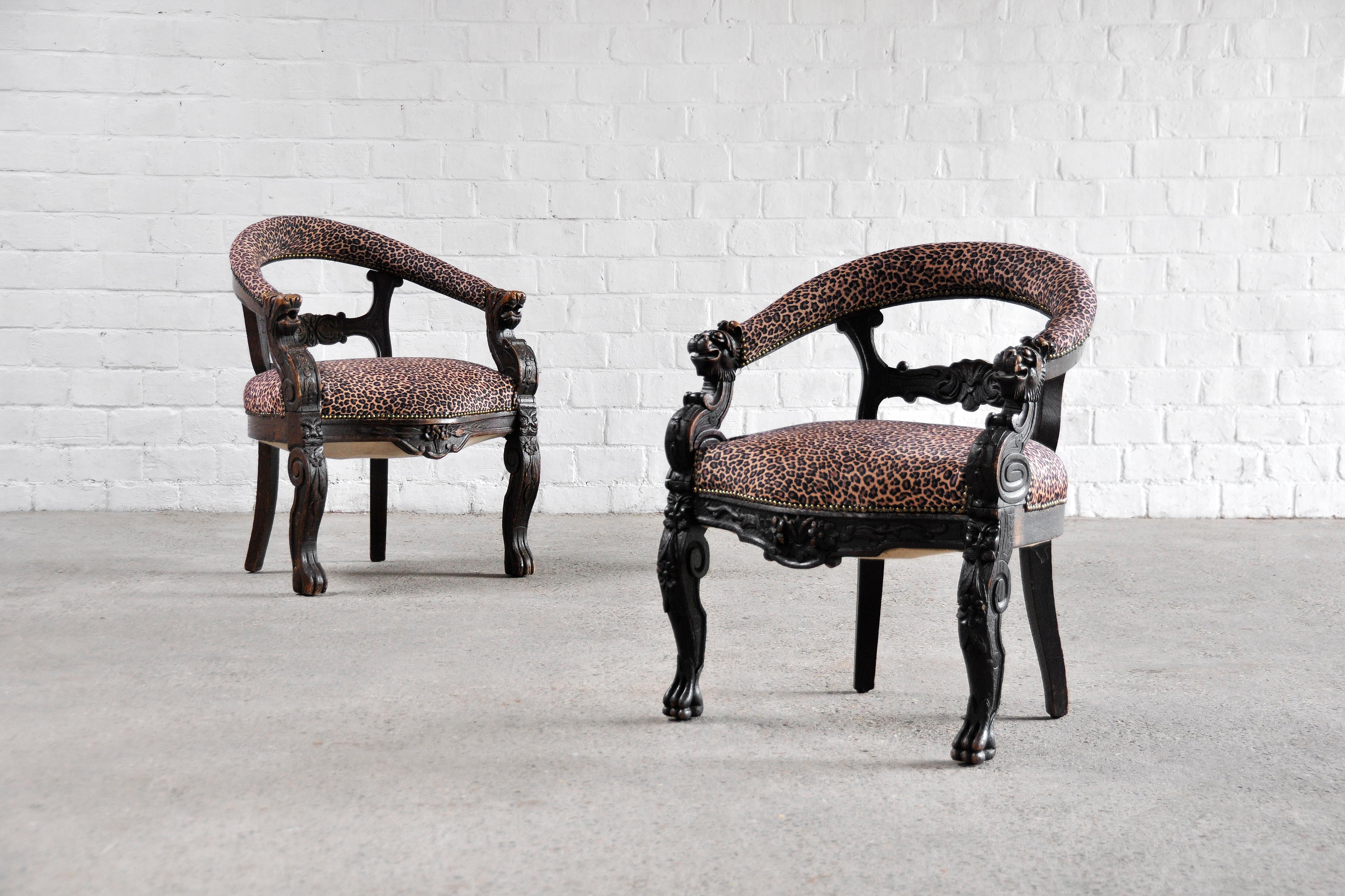 A near pair of Renaissance style chairs with richly carved frames. These oak tub chairs were made in the 19th century. The chairs feature a more recent upholstery with leopard imitation print. A stunning set that will no doubt be the center of