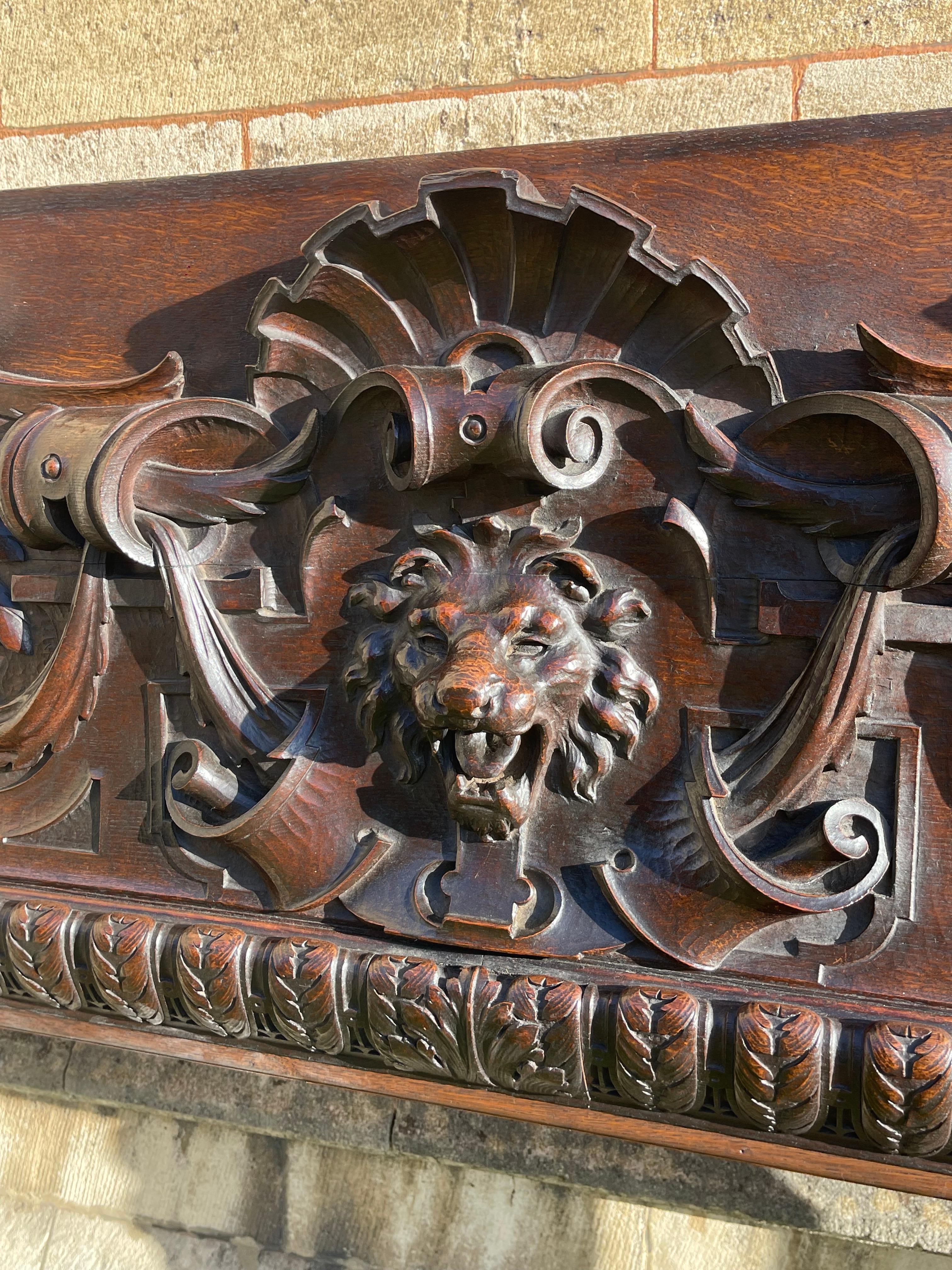 Grand panneau d'encadrement de cheminée en chêne finement sculpté de style renaissance. Profondément sculpté d'un masque de lion et de guirlandes au centre, sous le surplomb d'une coquille. Soutenu par des gryfons mythiques ailés qui portent chacun