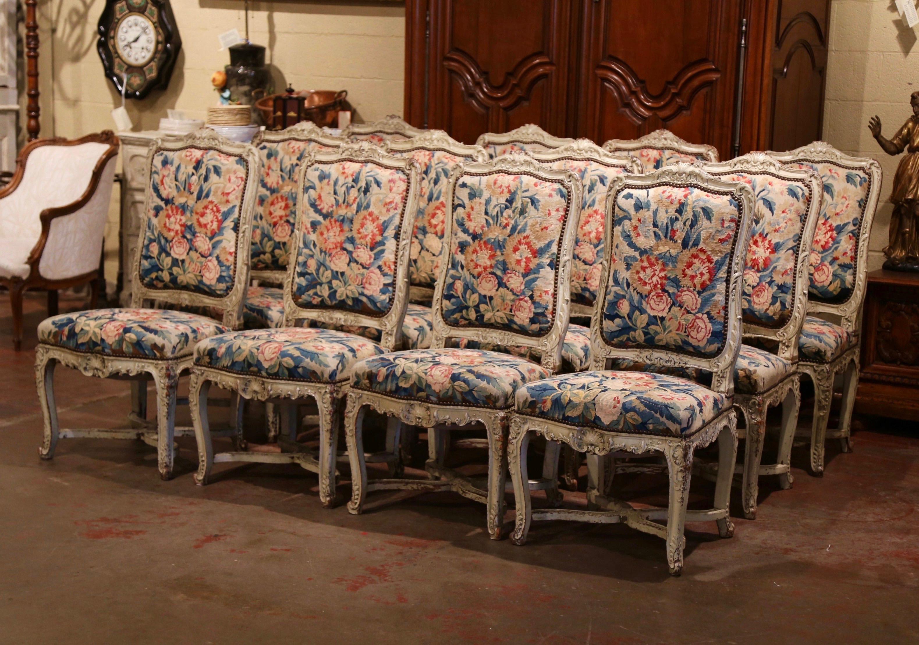 Decorate a dining room with this exceptional suite of antique chairs; crafted in Paris, France, circa 1820, the large twelve chairs Stand on cabriole legs decorated with acanthus and floral motifs, over a X stretcher embellished with a central