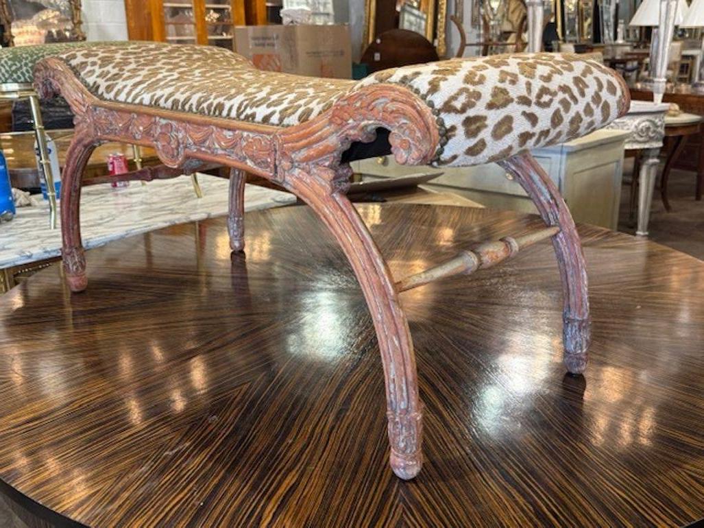 This 19th century Italian carved polychrome bench is a stunning piece of antique furniture, featuring intricate carvings and luxurious Scalamandre fabric upholstery. The bench exudes a sense of elegance and history, making it a unique and