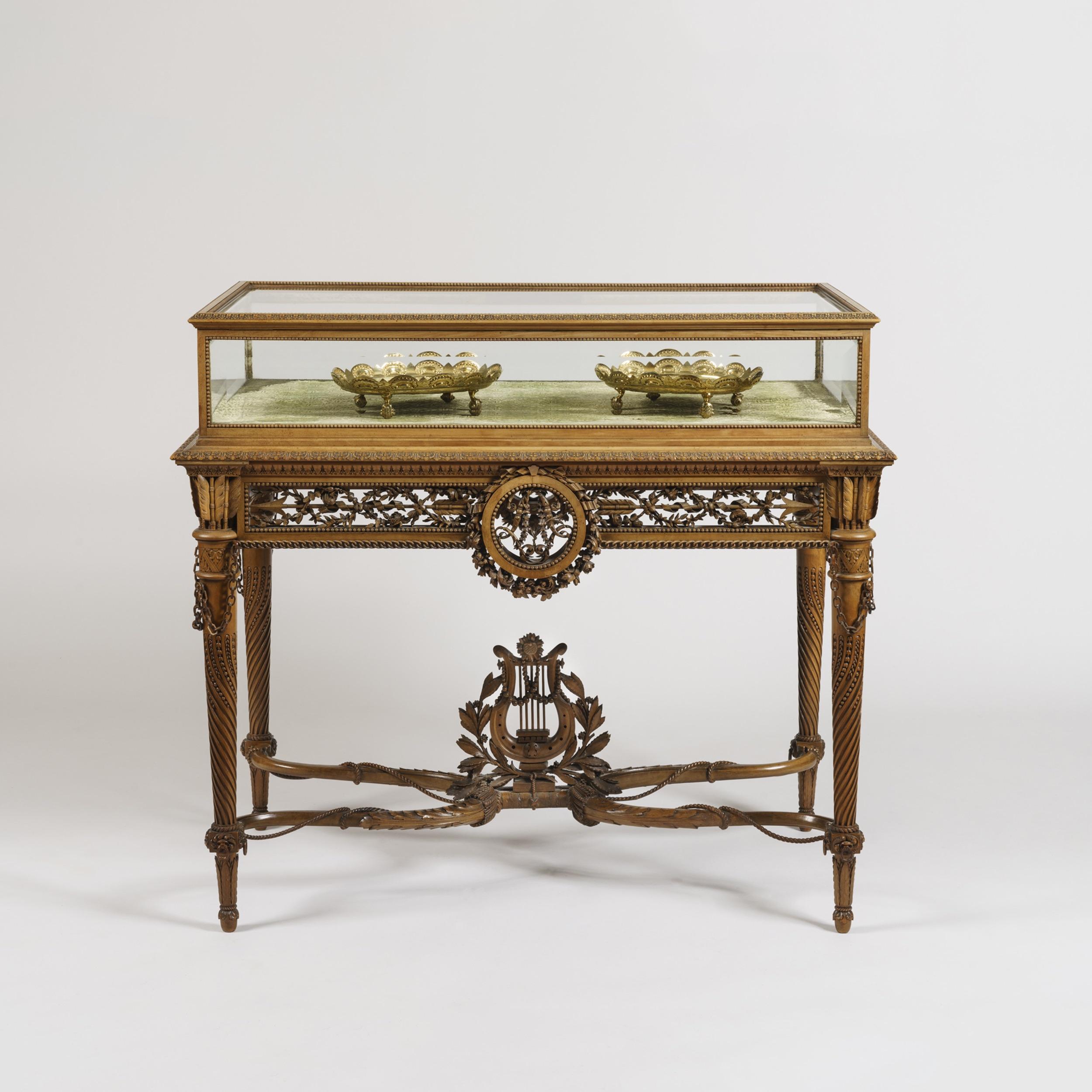 A Tour de Force table Vitrine in the Louis XVI Manner
by Alfred-Emmanuel-Louis Beurdeley, of Paris

Of free-standing form, constructed in a finely patinated fruit wood, adorned with carving of finest Exhibition quality; rising from tapering, turned