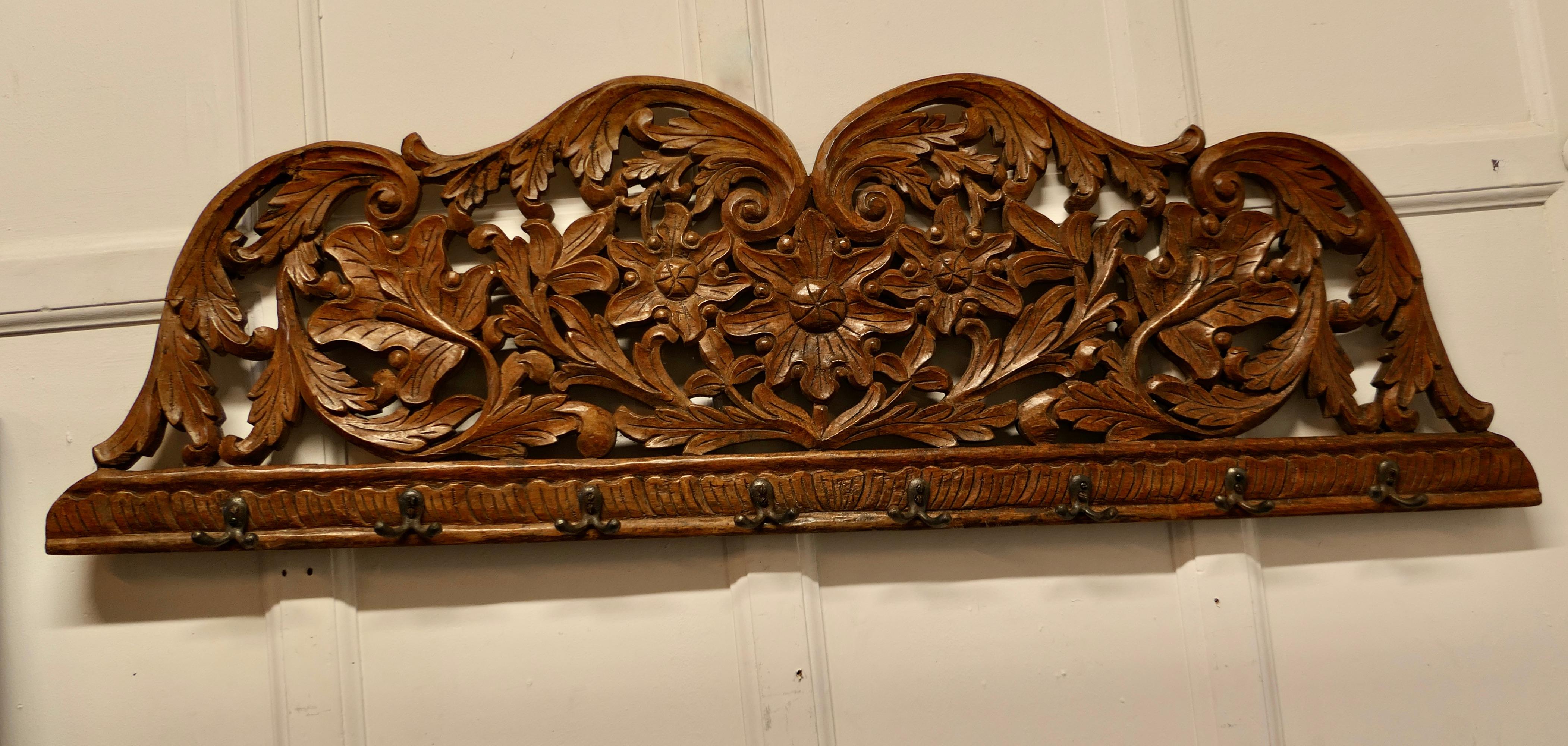 19th century Carved teak wall hanging coat rack.

 19th century Carved wall hanging coat rack for coats umbrellas or hats.

This is a solid carved wall piece, it is profusely carved with leaves and flowers, below there are 8 double hooks.
The