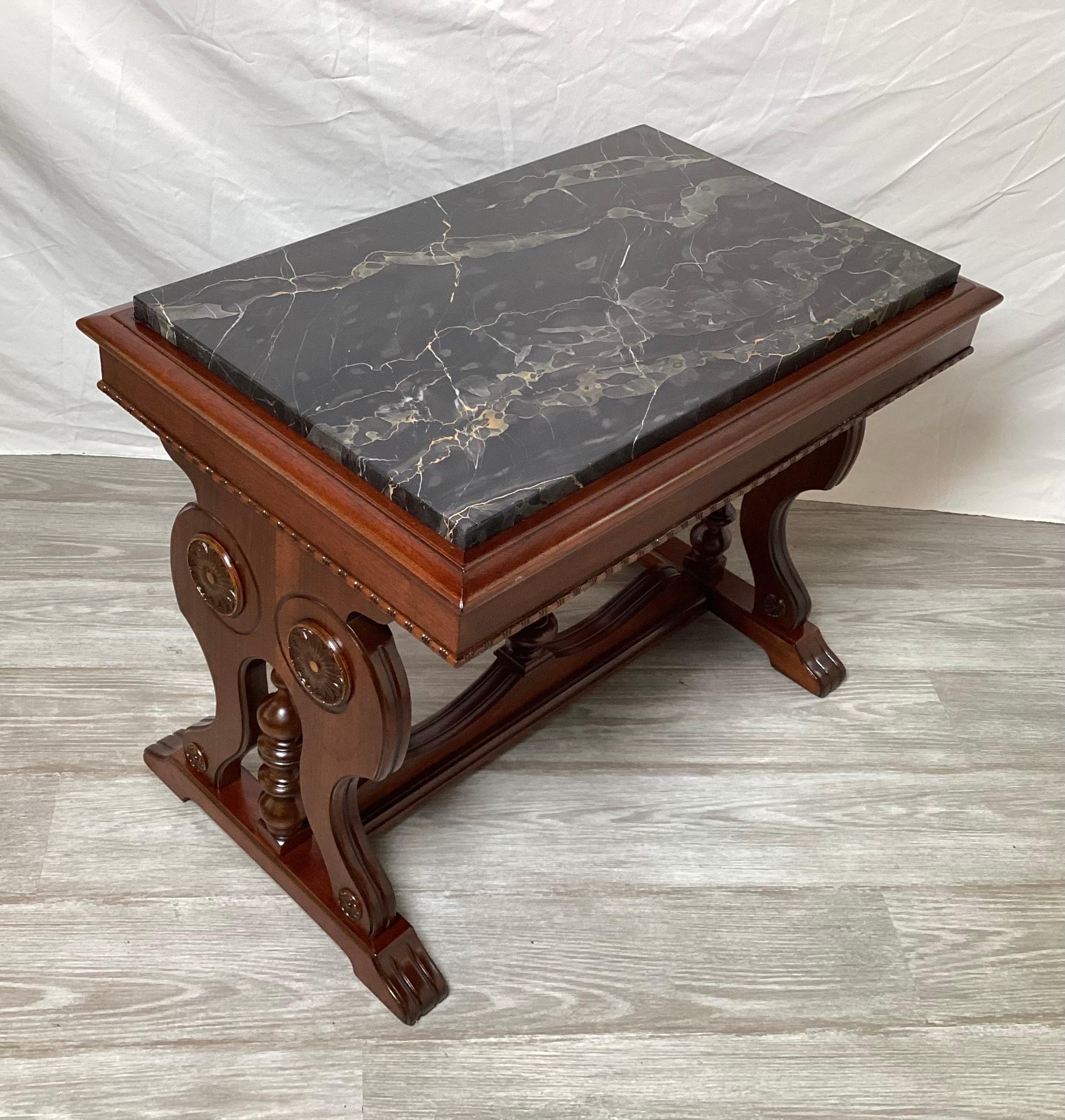 Beautifully carved walnut table with black marble top. The shield form sides with carved medallions with inset marble top.