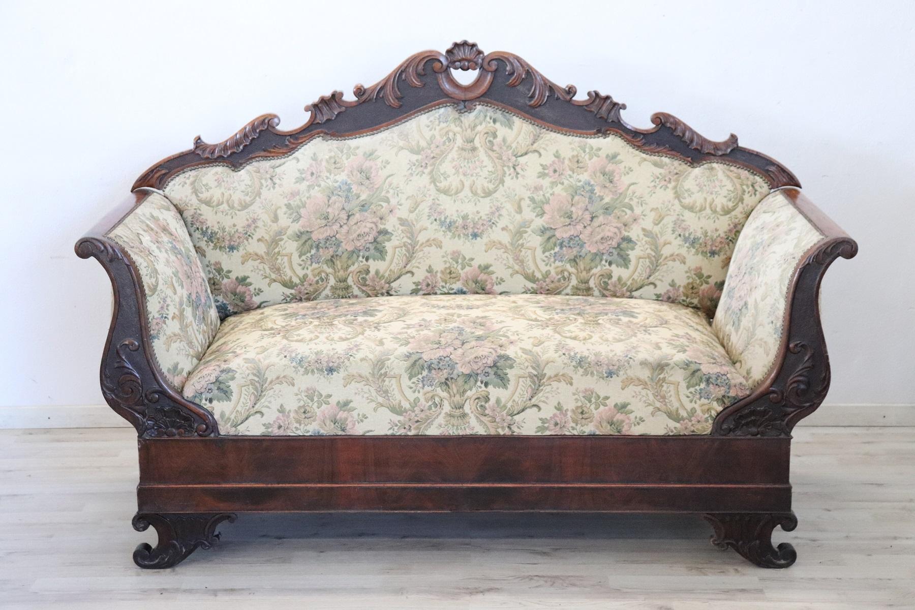 Antique settee 1825s in full Charles X era. The settee is made of solid walnut hand carved. Ancient fabric with floral decoration. Excellent condition of the wood, signs of wear on the fabric.