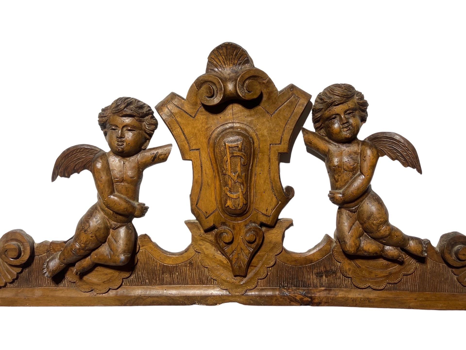A lovely 19th century French Renaissance Revival architectural fragment depicting two winged putti or cherubs flanking a central monogramed cartouche. This carving was likely from an elaborate piece of furniture and made into a wall carving in the