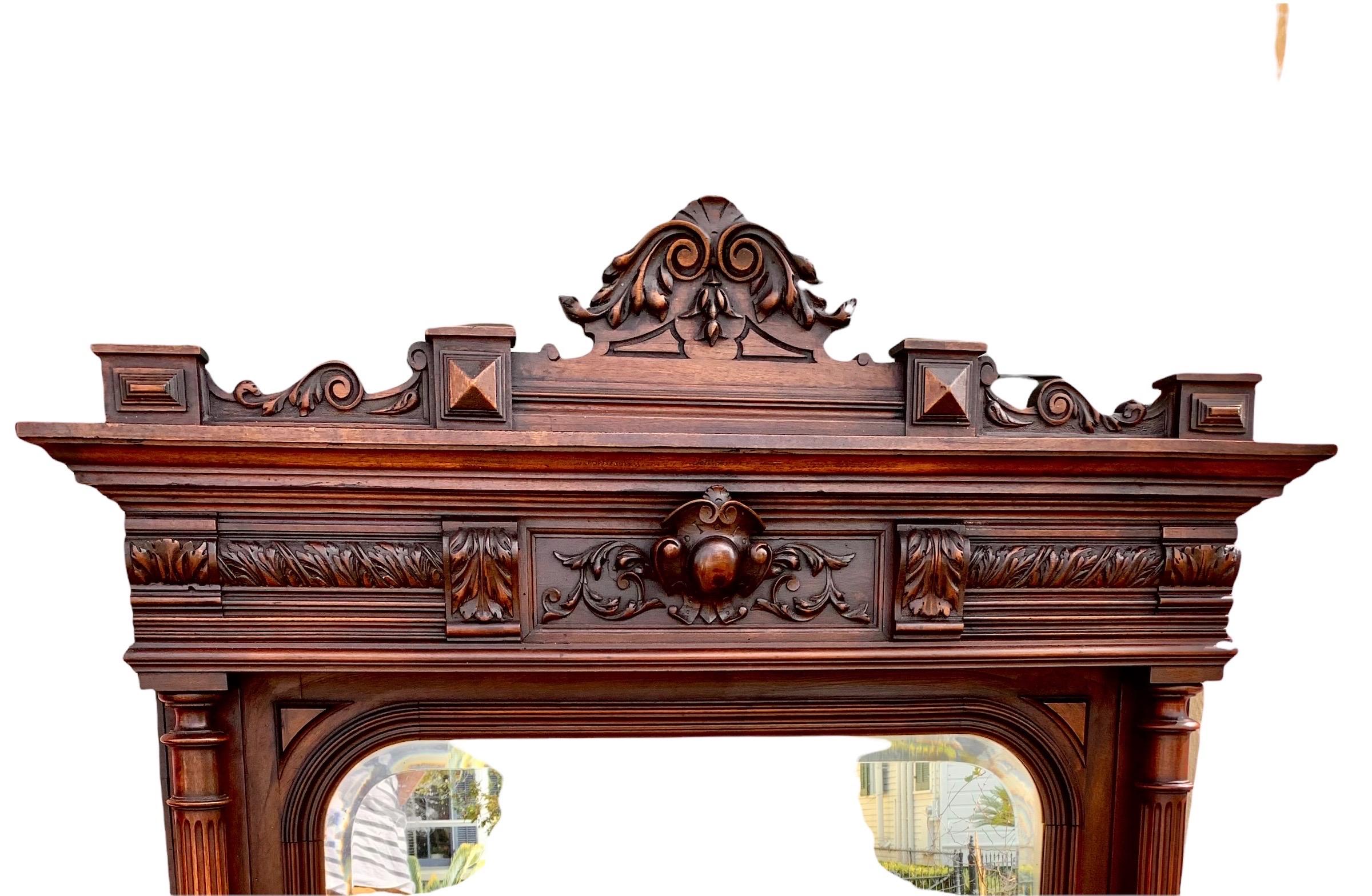 Antique French Renaissance Revival hand carved walnut over mantle mirror with a stunning, original double beveled shaped mirror plate, flanked by fluted columns, the crown having a center carved cartouche and scrolled elements.

This lovely mirror