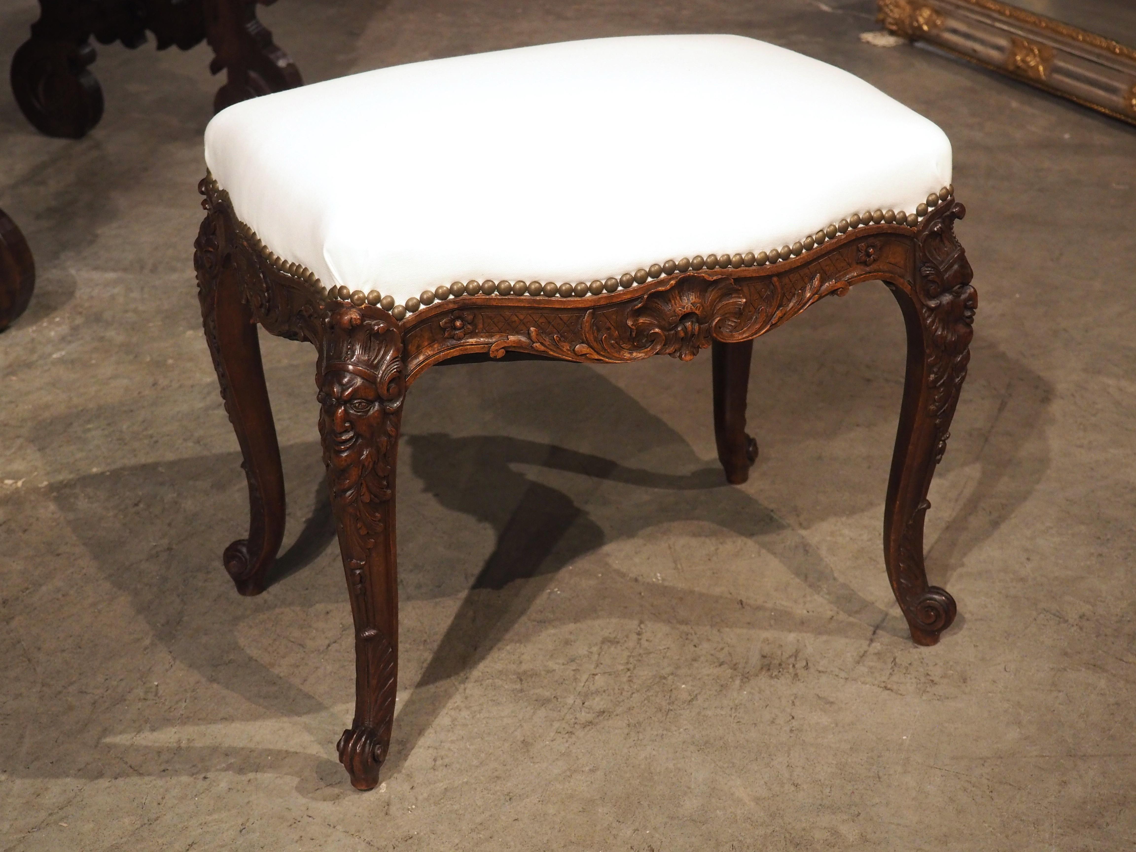 Meticulously hand-carved from rich walnut wood in France during the 1800s, this Regence-style tabouret exudes elegance. Recently upholstered in a crisp, cotton fabric, the juxtaposition of the true white against the dark brown wood patina creates a