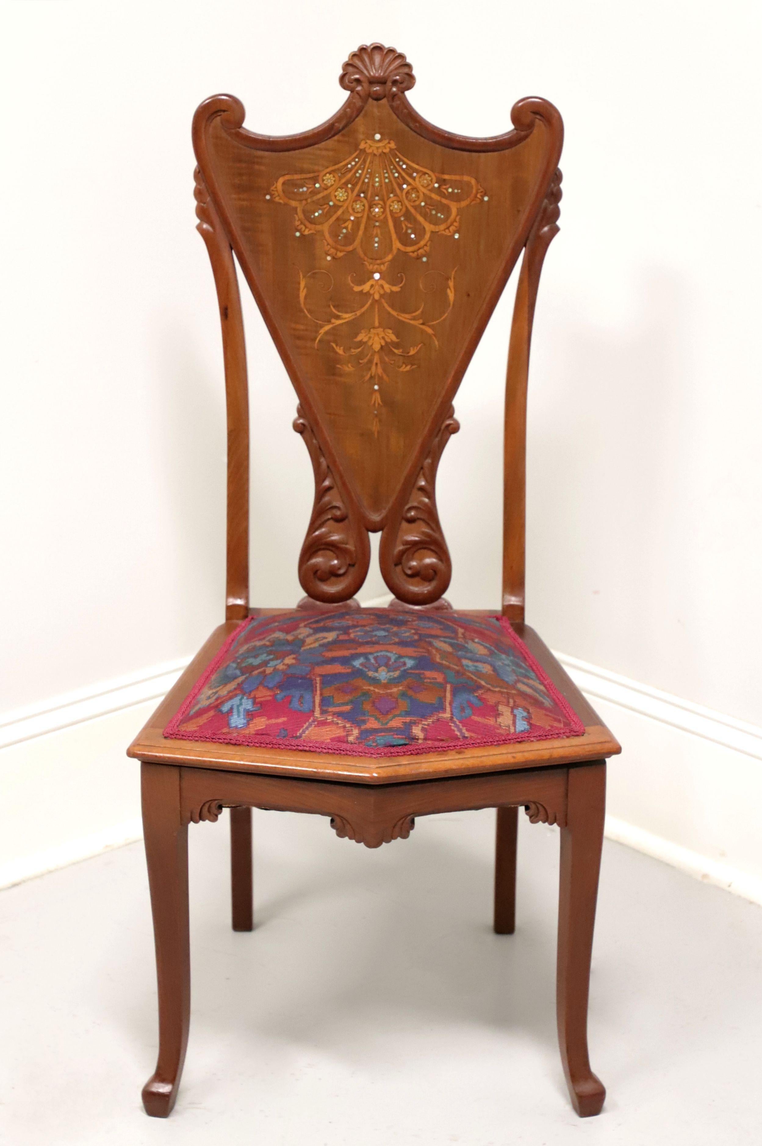 An antique Victorian style side chair, unbranded. Hand carved & crafted of walnut with mother of pearl inlays, decoratively carved shield back, upholstered seat in a multi-color cross stitch fabric, carved apron, slightly curved front legs and pad