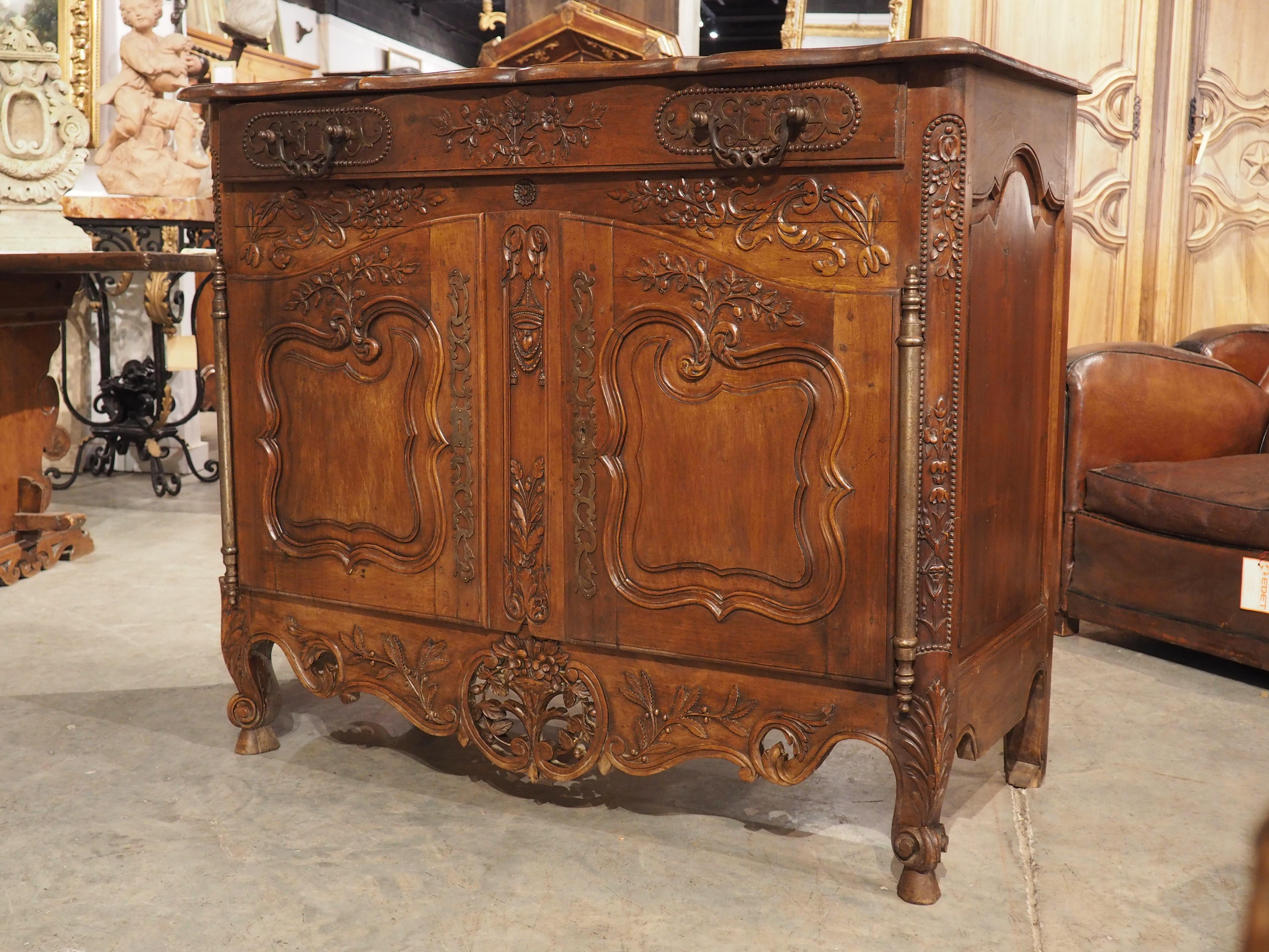 Buffets from Provence have a distinct style, often featuring carved motifs relating to nature and agriculture. This walnut buffet from the 1800s is no exception, as noted by the highly detailed apron, which is highlighted by a pierced bouquet