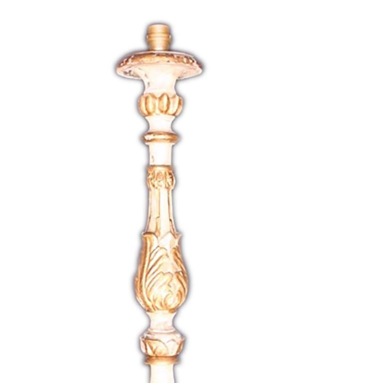 This 19th century carved wood and gilt candlestick has been converted into a lamp. A tall slender piece supported by four legs tapering to curls. This piece features carved decoration from top to bottom including leaf motifs.