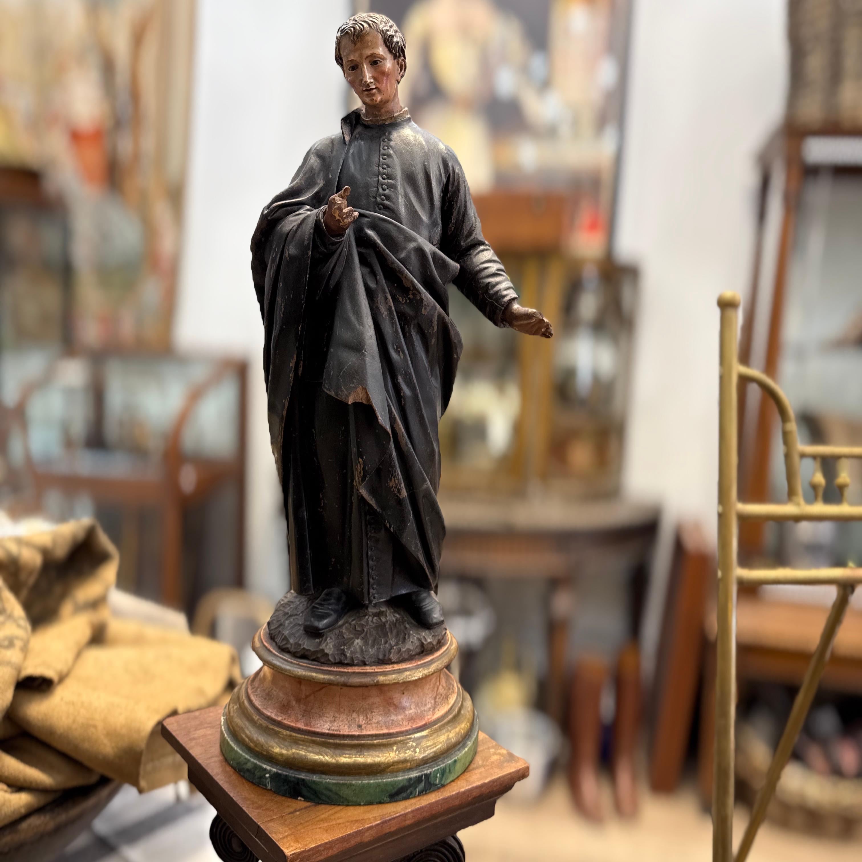 Eine fein geschnitzte Holzstatue eines männlichen Heiligen, wahrscheinlich aus Frankreich, aus dem 19. Jahrhundert. Diese Andachtsfigur ist in einem klerikalen Gewand mit zarten Gesichtszügen, eingesetzten Glasaugen und originaler polychromer und