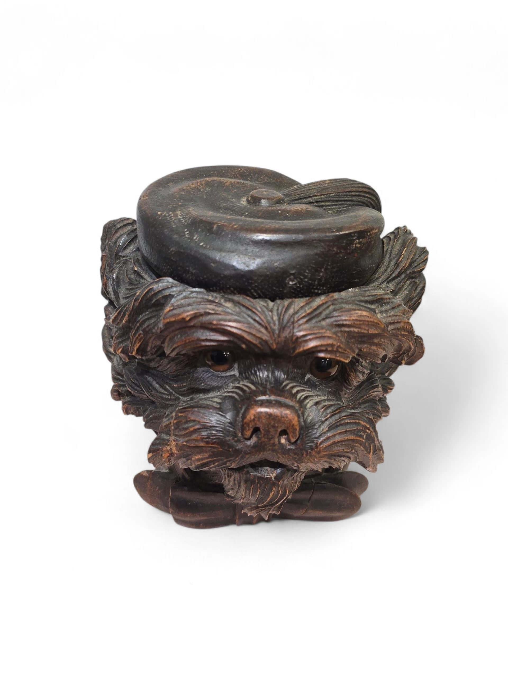 Charmante boîte à tabac en bois du XIXe siècle, finement sculptée en forme de tête de chien, avec des yeux en verre et une exécution détaillée.
Cette pièce expressive et pleine de caractère témoigne de l'art et de l'humour typiques de la sculpture