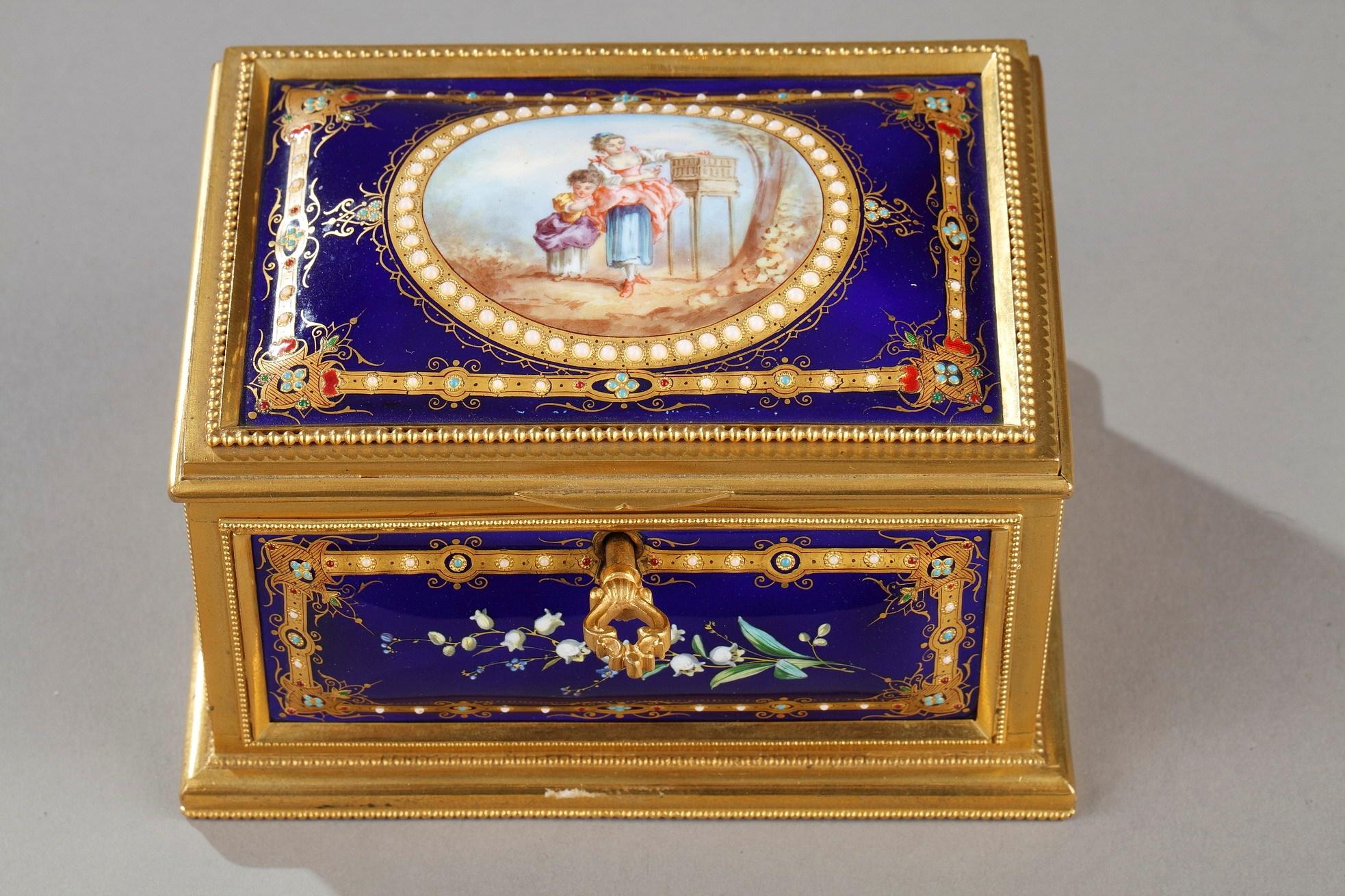 A small rectangular casket in enamel and gilt bronze decorated with pearl garland motifs and set with five enameled plates. The lid is decorated with a blue enameled plate with a medallion in the center depicting two young girls in 18th century