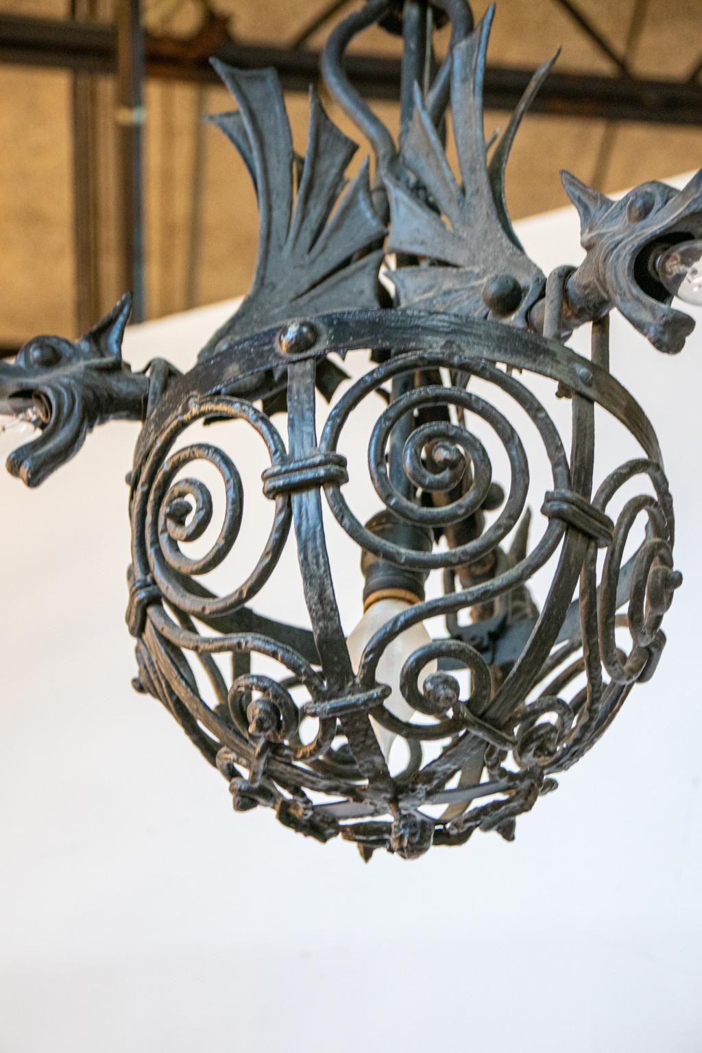 Circa 19th century cast iron and wrought iron hanging light fixture in the Gothic Revival style. The piece features three stylized winged gargoyles mounted on top of an s-scroll wrought iron dome chandelier with light bulb hardware inside their