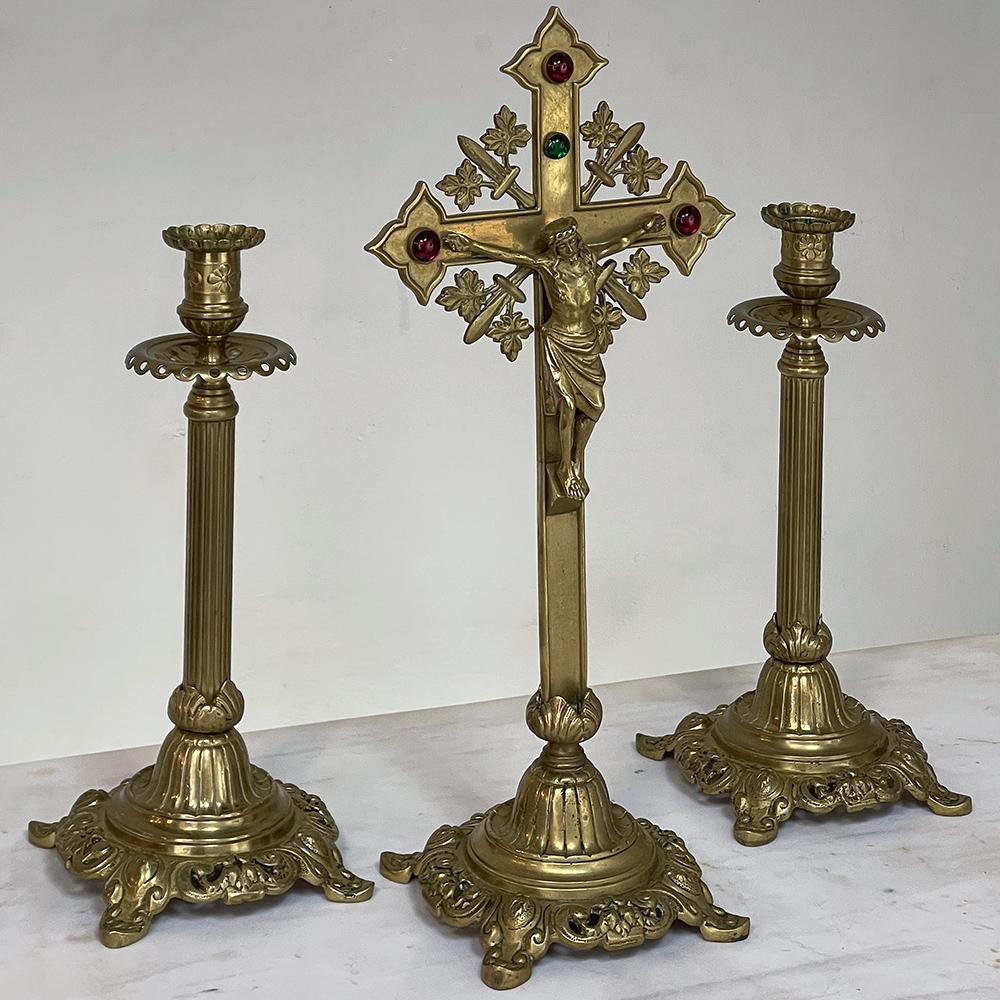 19th Century cast brass crucifix with pair of matching candlesticks is an exceptional example of the metalsmith's art! The crucifix features trefoils at the tips of the cross, representing the Holy Trinity, accented with garnet-colored mabe glass,