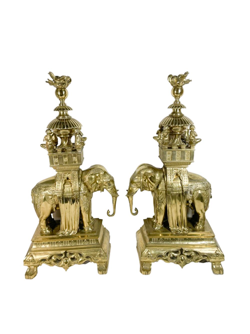 A large pair of cast brass garnitures or chenets in the Orientalist or Anglo-Indian taste featuring full bodied caparisoned elephants carrying an elaborate howdah (saddle) with a scholar seated at each corner beneath a central domed cover and topped