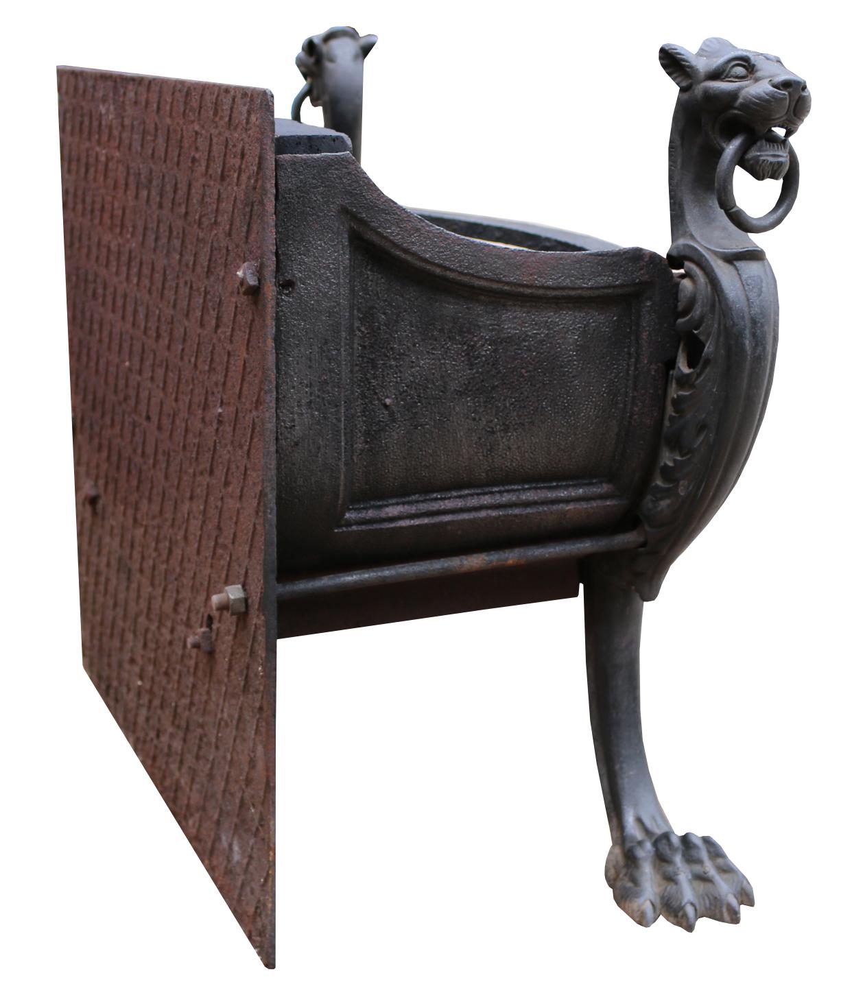 Une grille de cheminée de style victorien rococo en fer et bronze. La grille à trois barreaux et à arc est soutenue par une paire de griffons monopodes tenant des anneaux dans leur bouche.